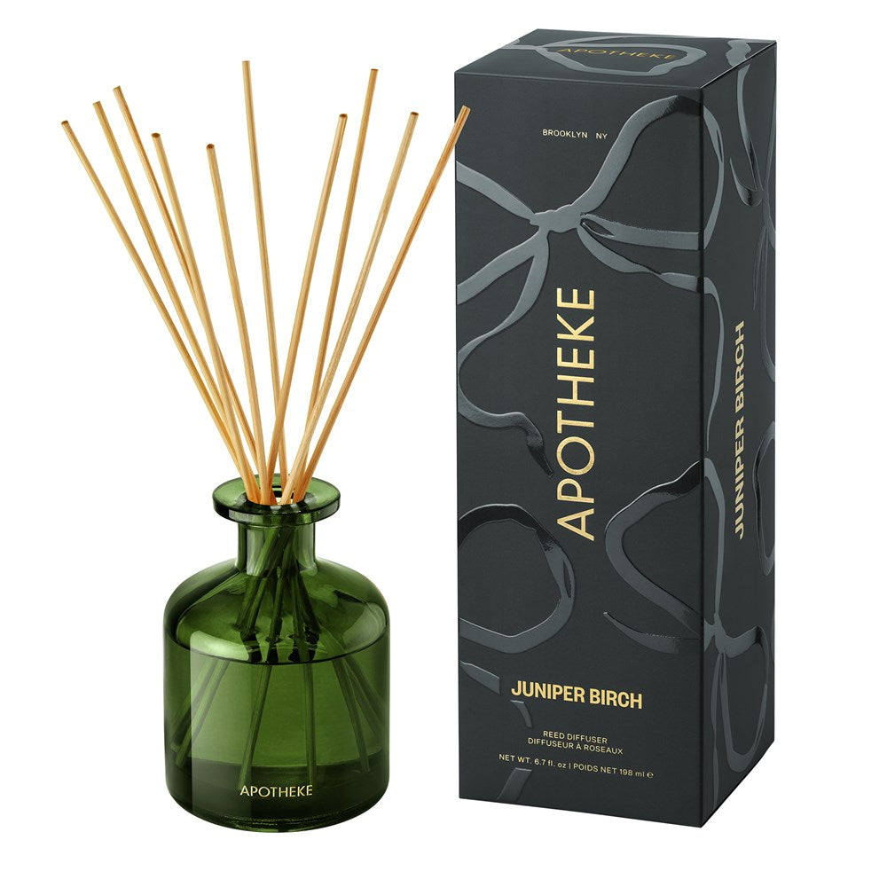 Green diffuser bottle with wooden sticks and black box labeled 'Apotheke' on a white background