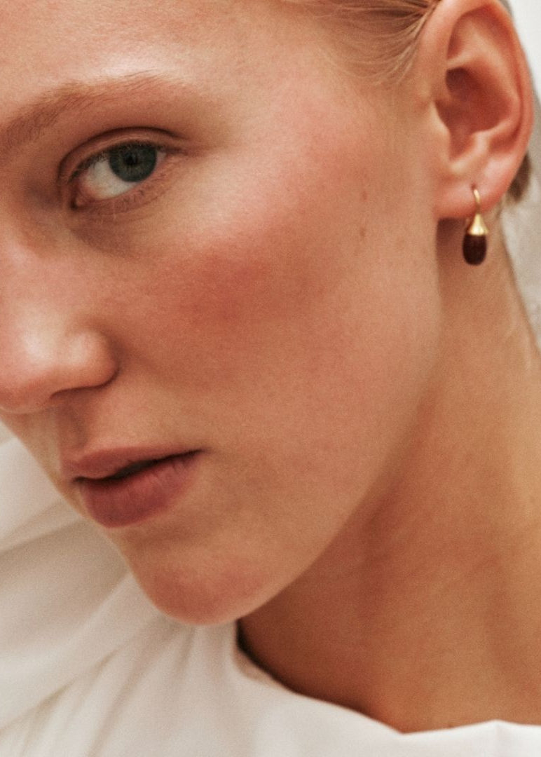 Close-up of a person wearing a gold earring with a white background
