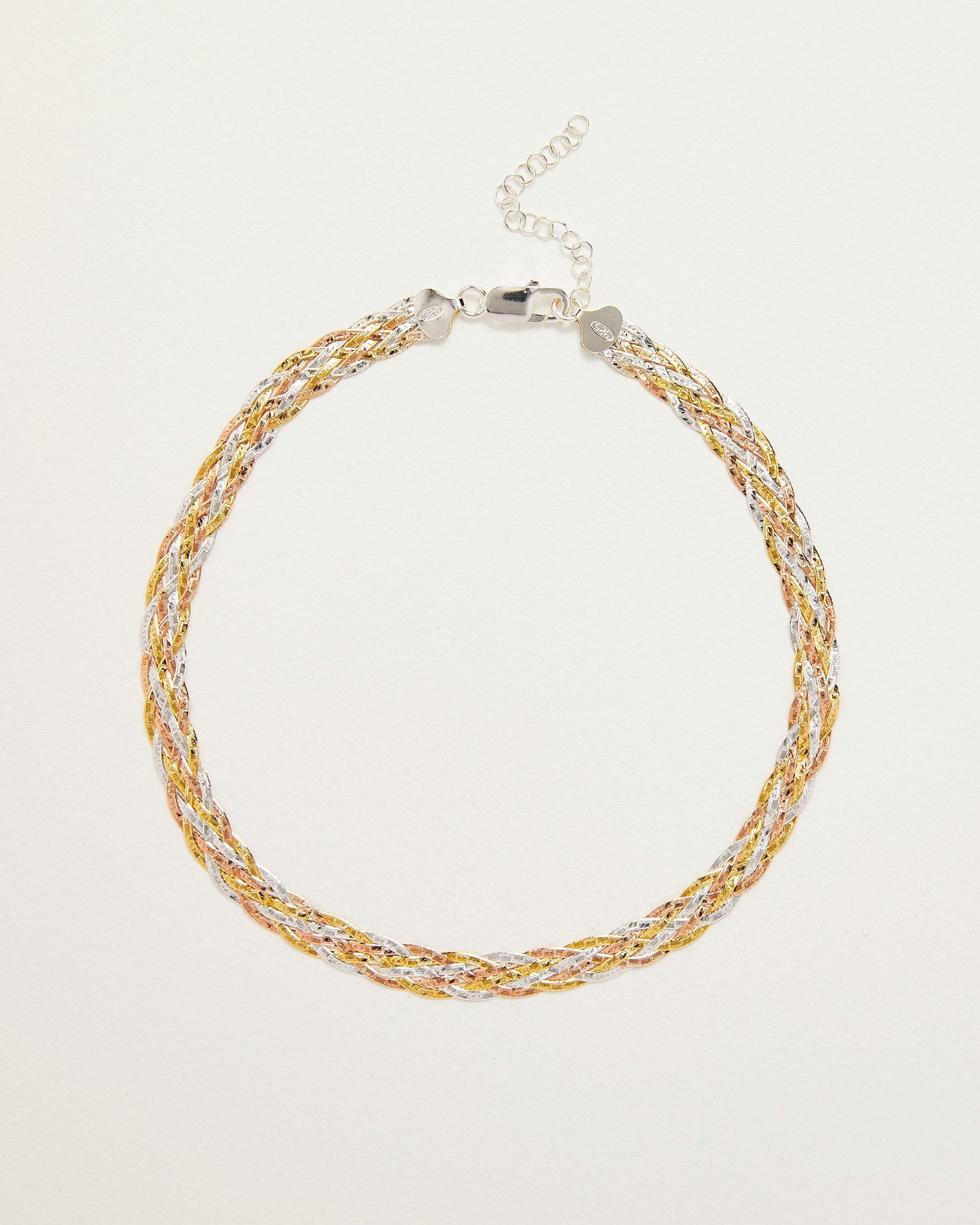 Gold and silver braided necklace on a light beige background