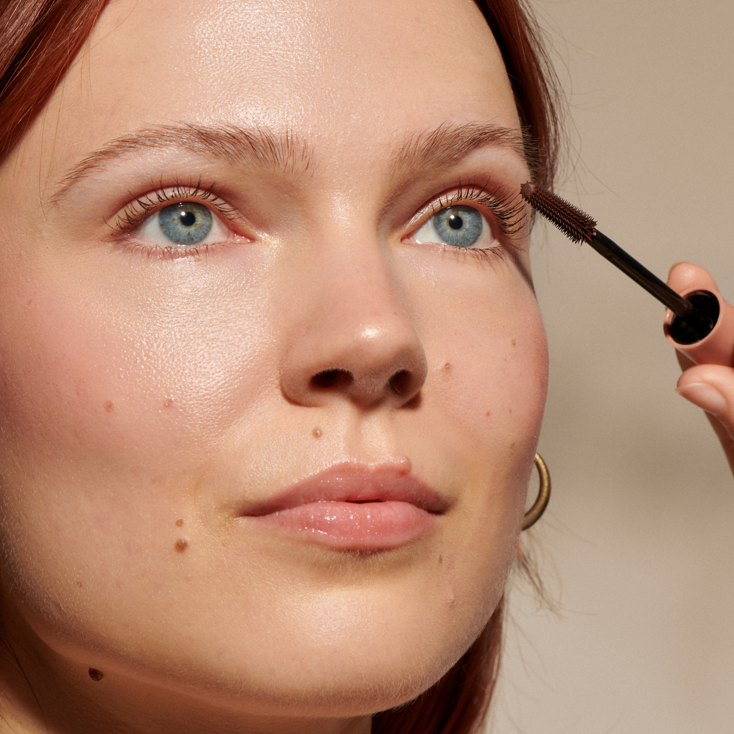 Close-up of a person applying mascara with a brush.