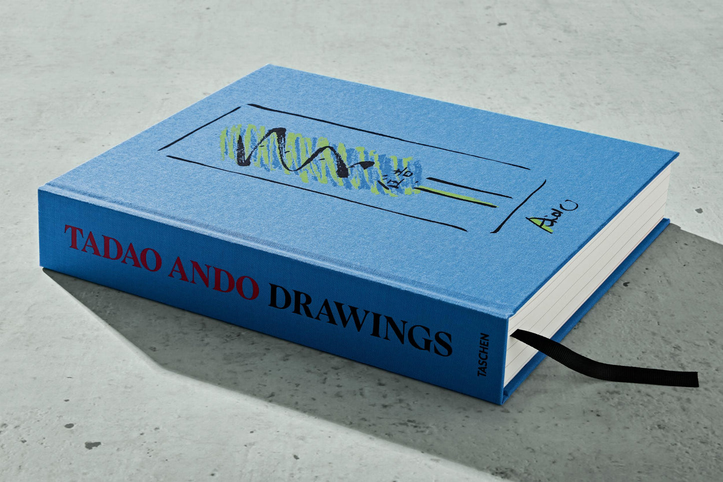 Blue book titled 'Tadao Ando Drawings' on a concrete surface