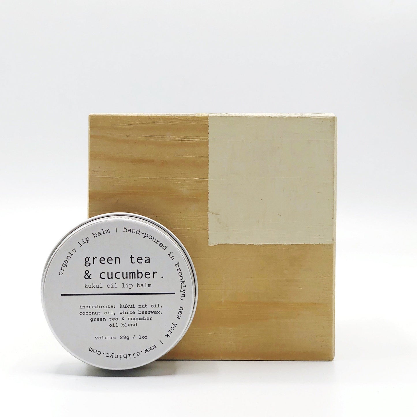 Lip balm with 'green tea & cucumber' label on a wooden block against a white background