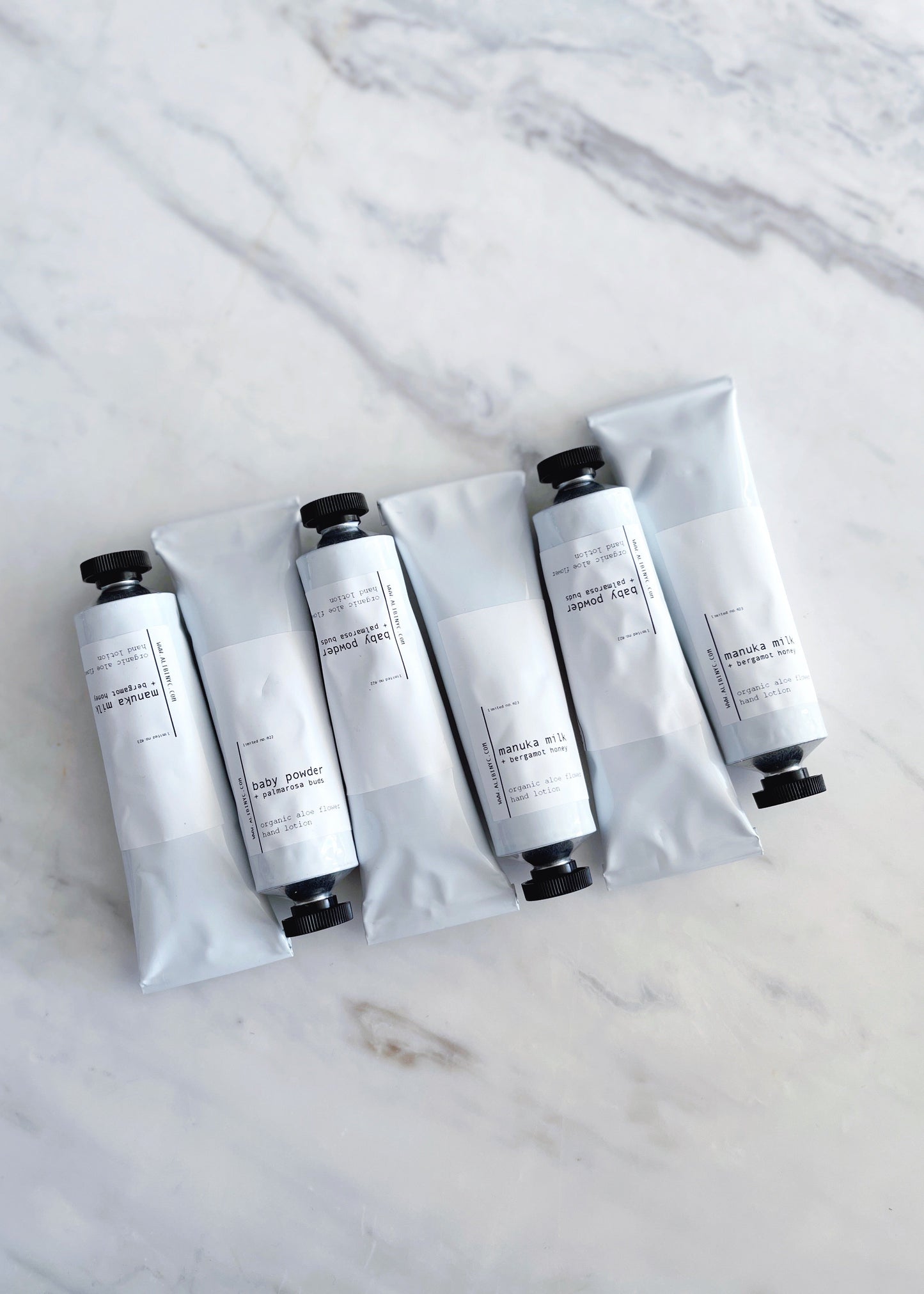 Five white tubes with black caps on a marble surface