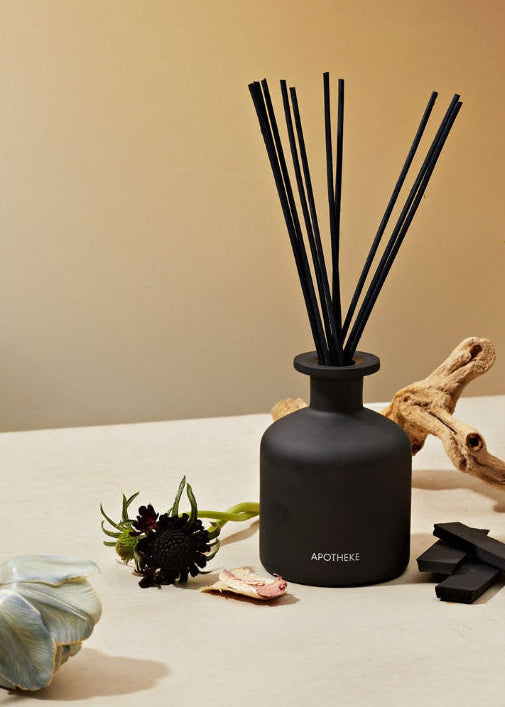 Black diffuser with sticks on a beige surface with decorative elements
