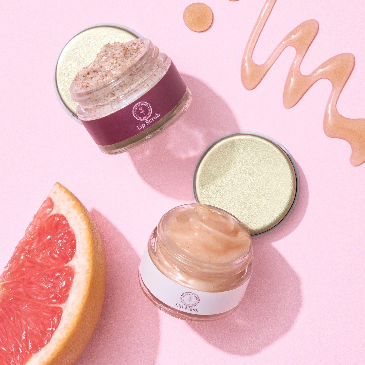 Two lip masks with a grapefruit on a pink background