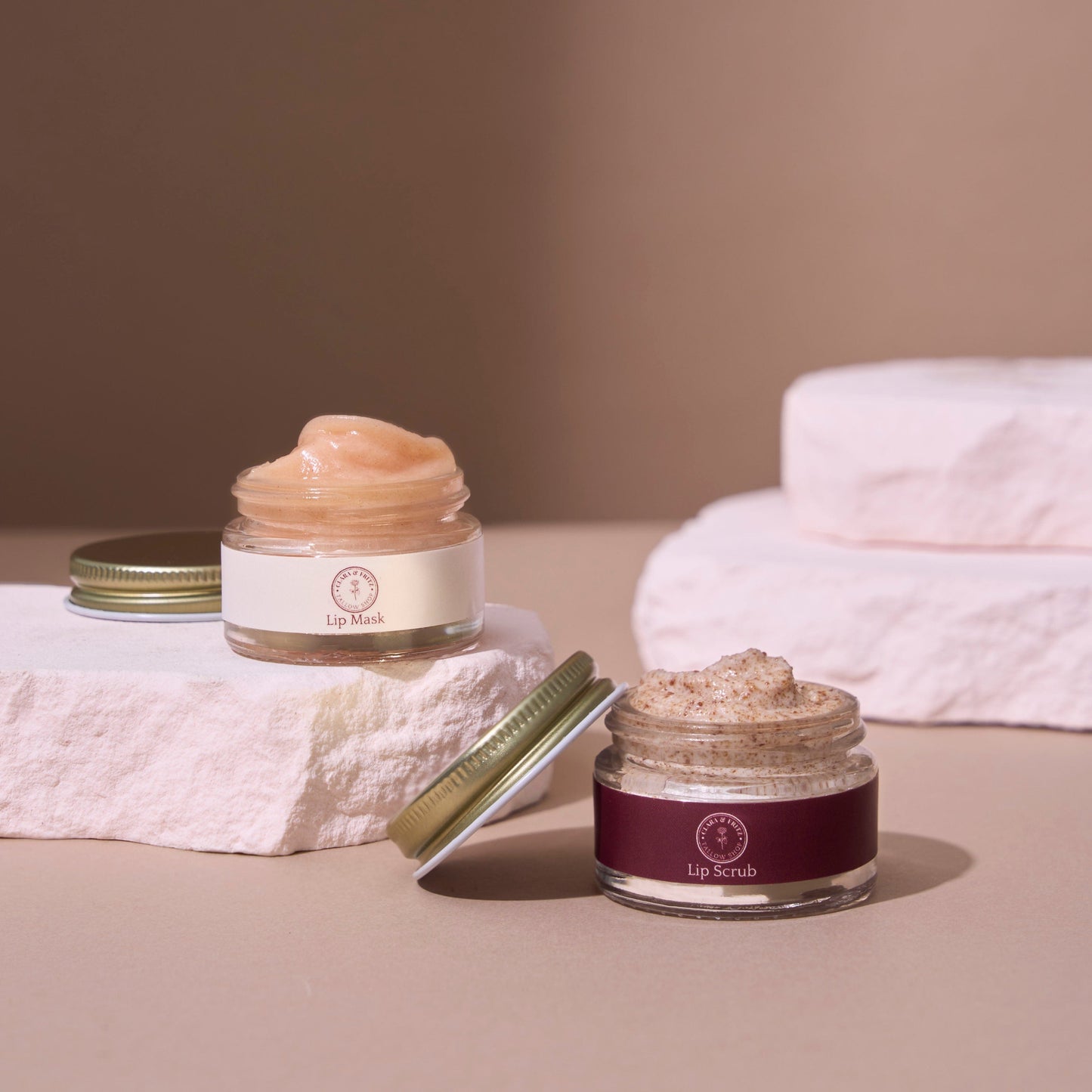 Two jars of lip care products on a neutral background