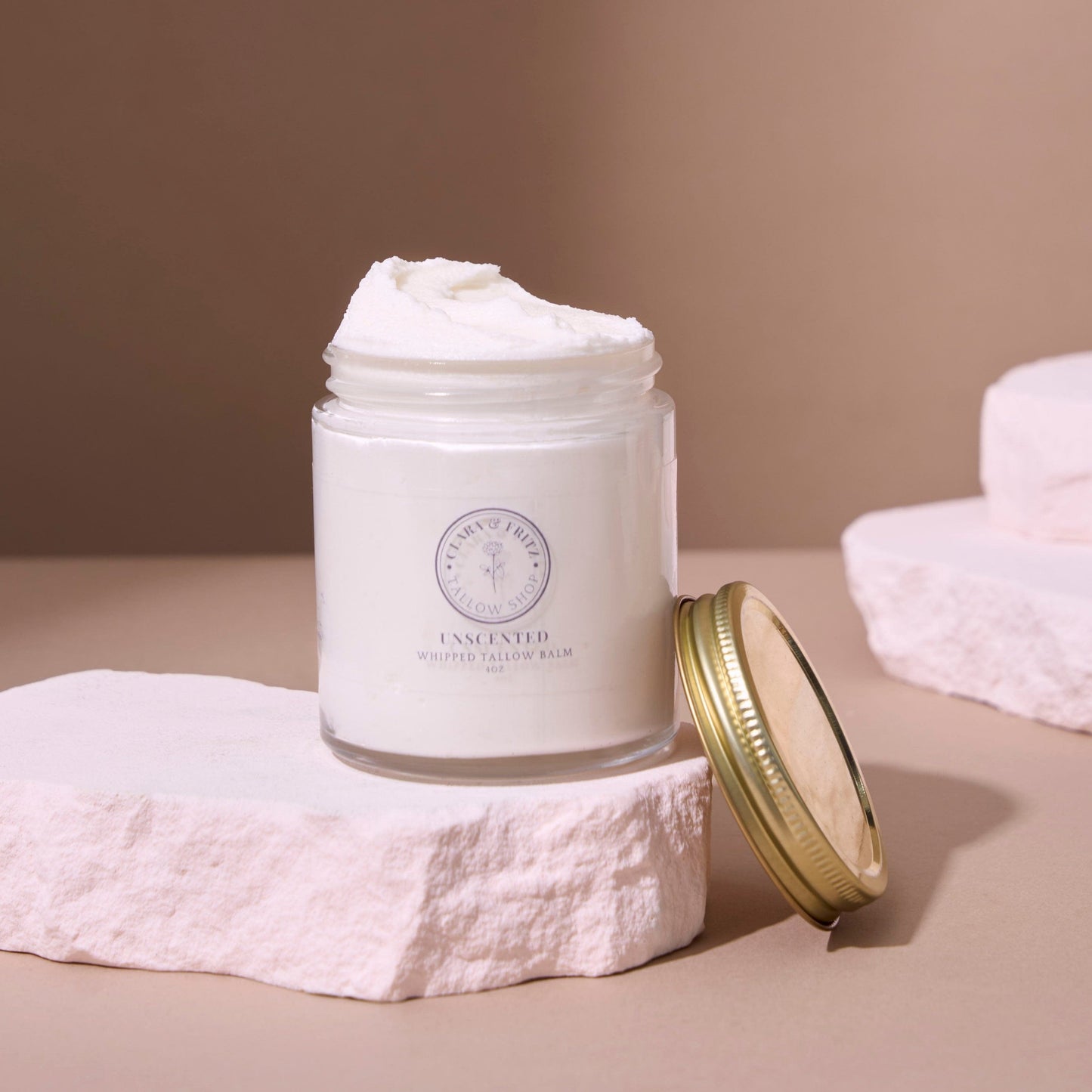 White jar of cream with a gold lid on a beige surface