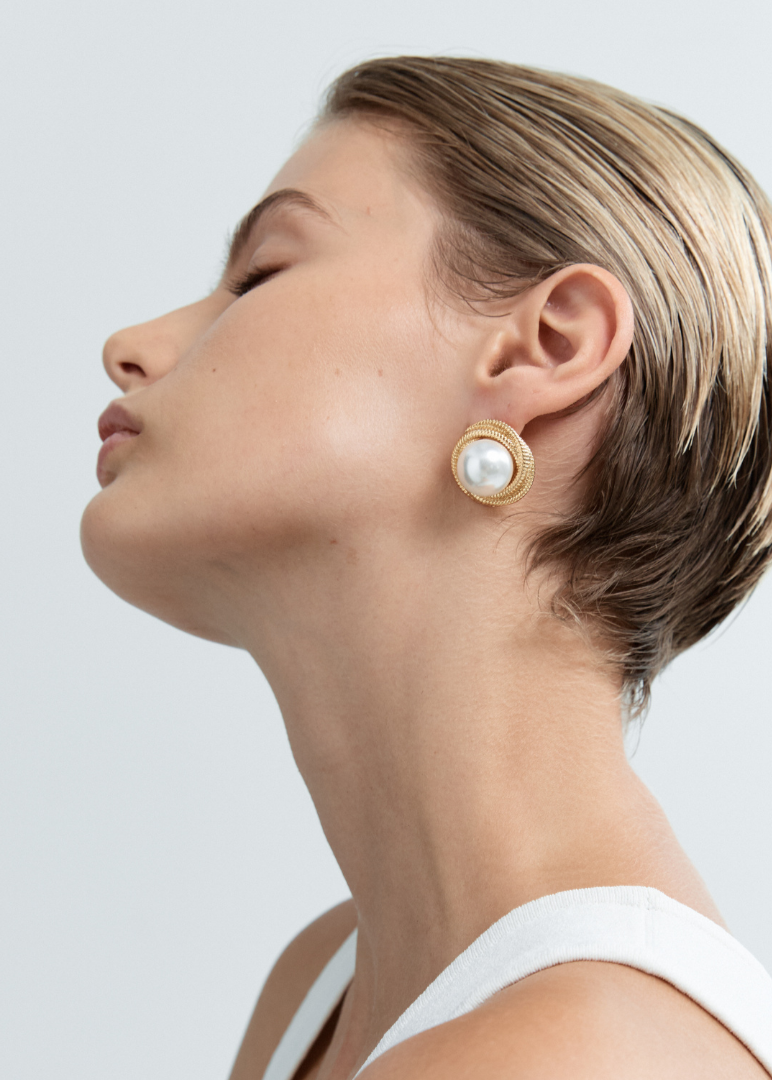 Woman wearing pearl earrings against a light background