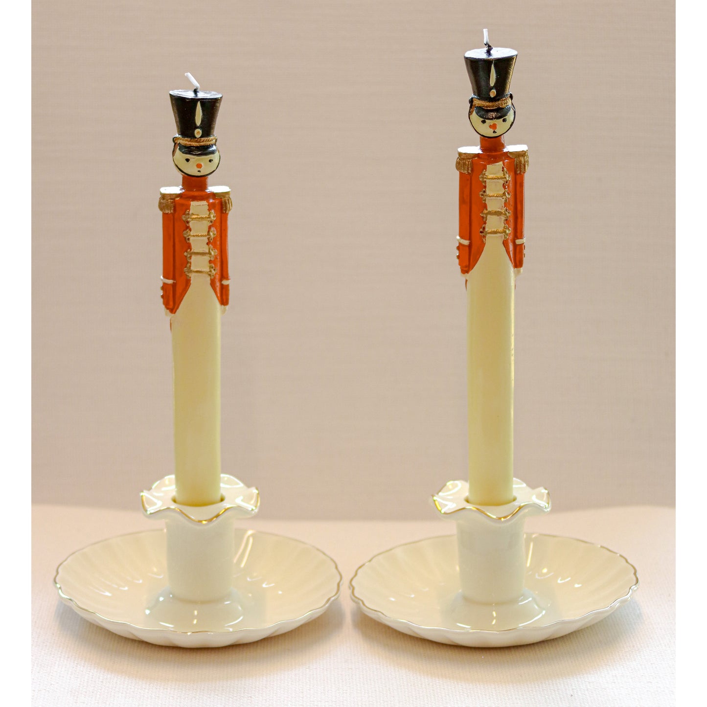 Two decorative candle in holders with nutcracker design on a beige background