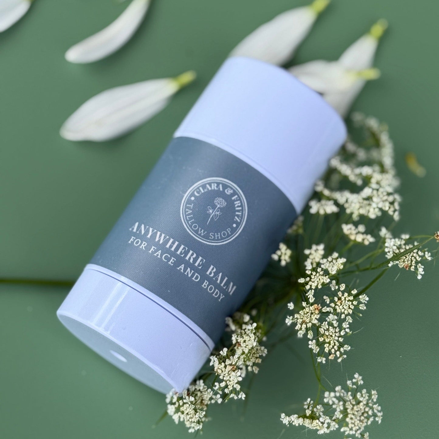 Balm tube labeled 'Anywhere Balm for Face and Body' by Lara & Ruth on a green background with flowers.