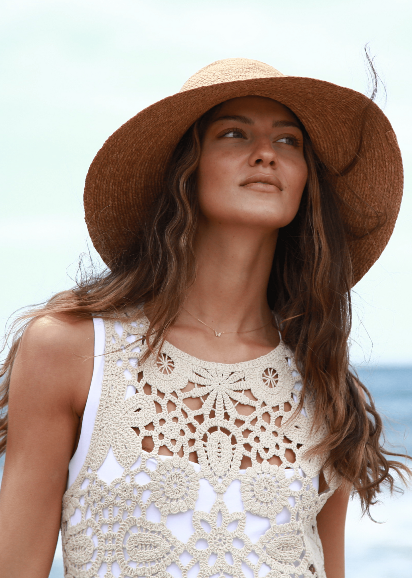 Woman wearing a straw hat and crochet top on a beach