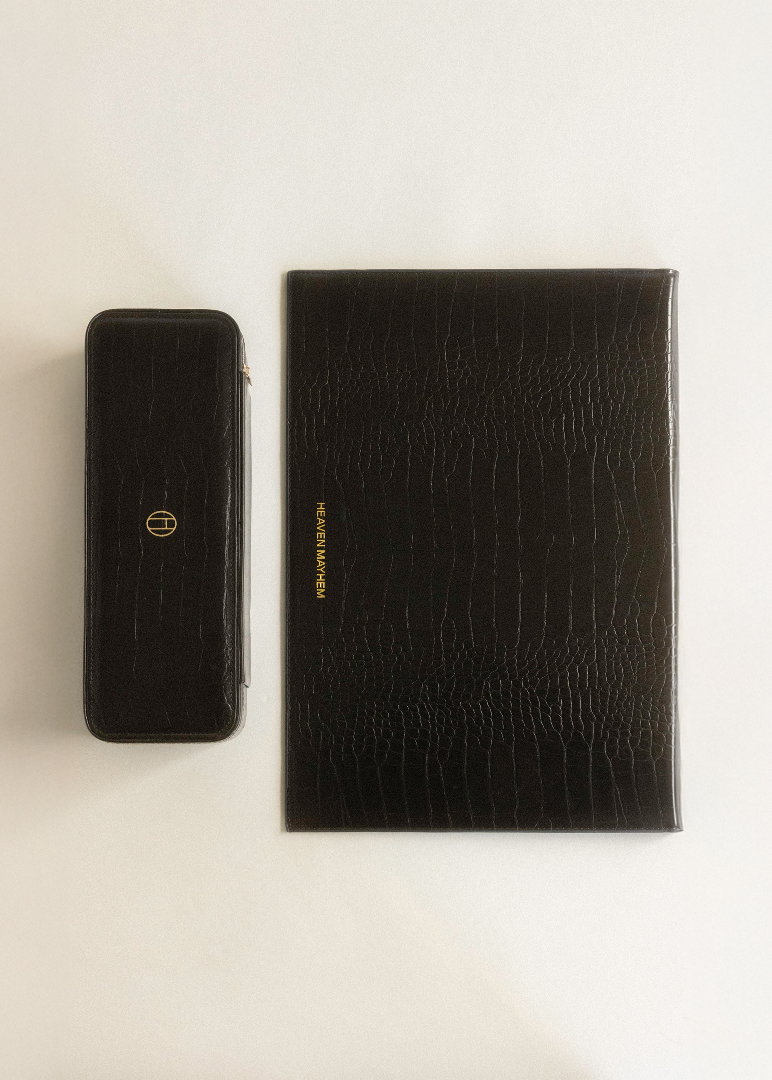 Two black leather cases with gold logos on a beige background