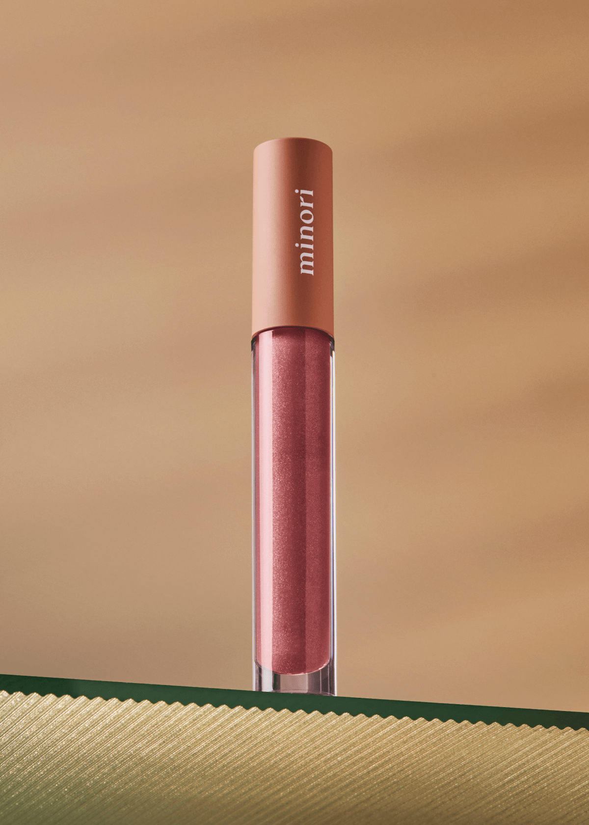 Lip gloss with 'minori' branding on a beige background