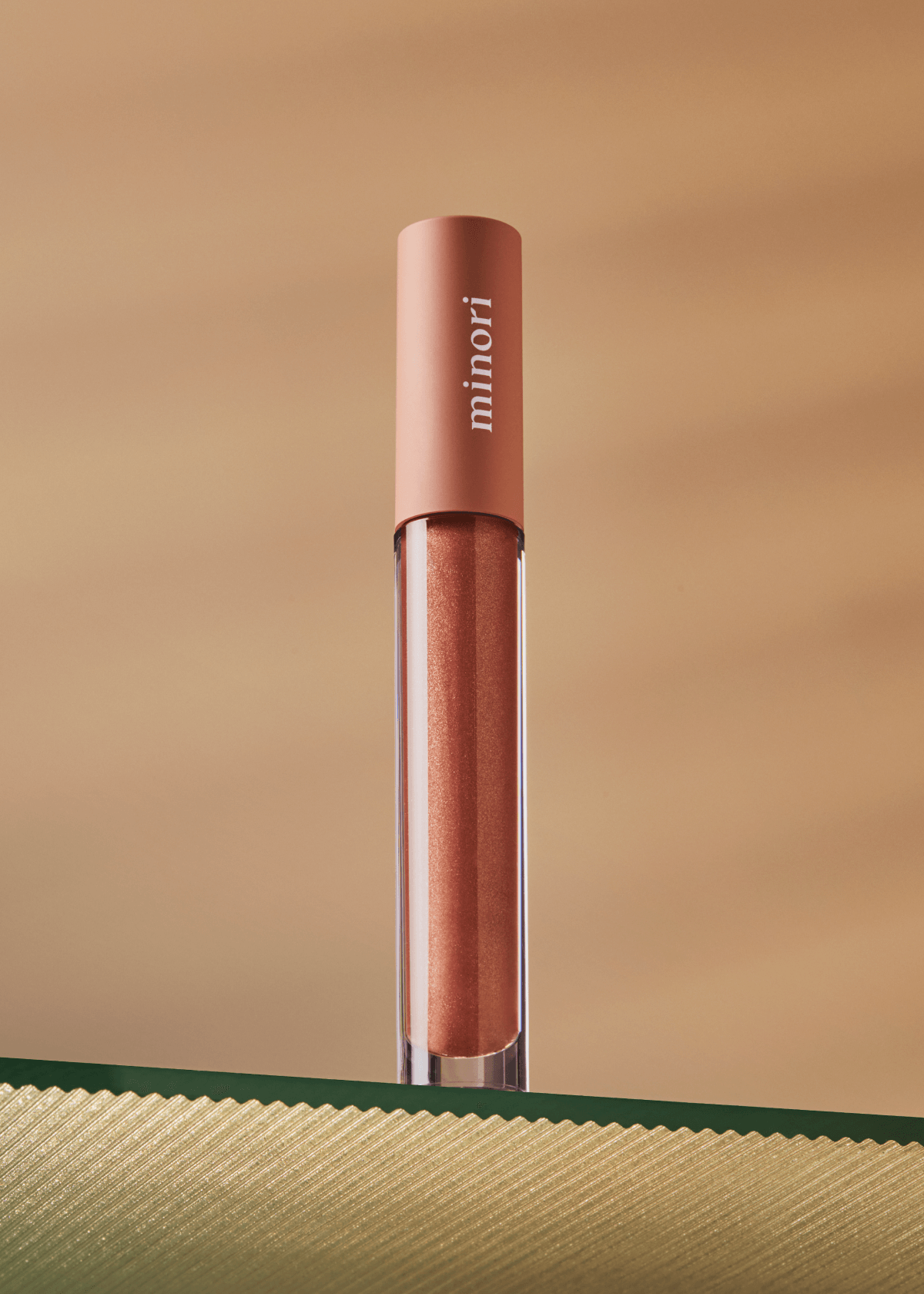 Lip gloss with 'minori' branding on a beige background