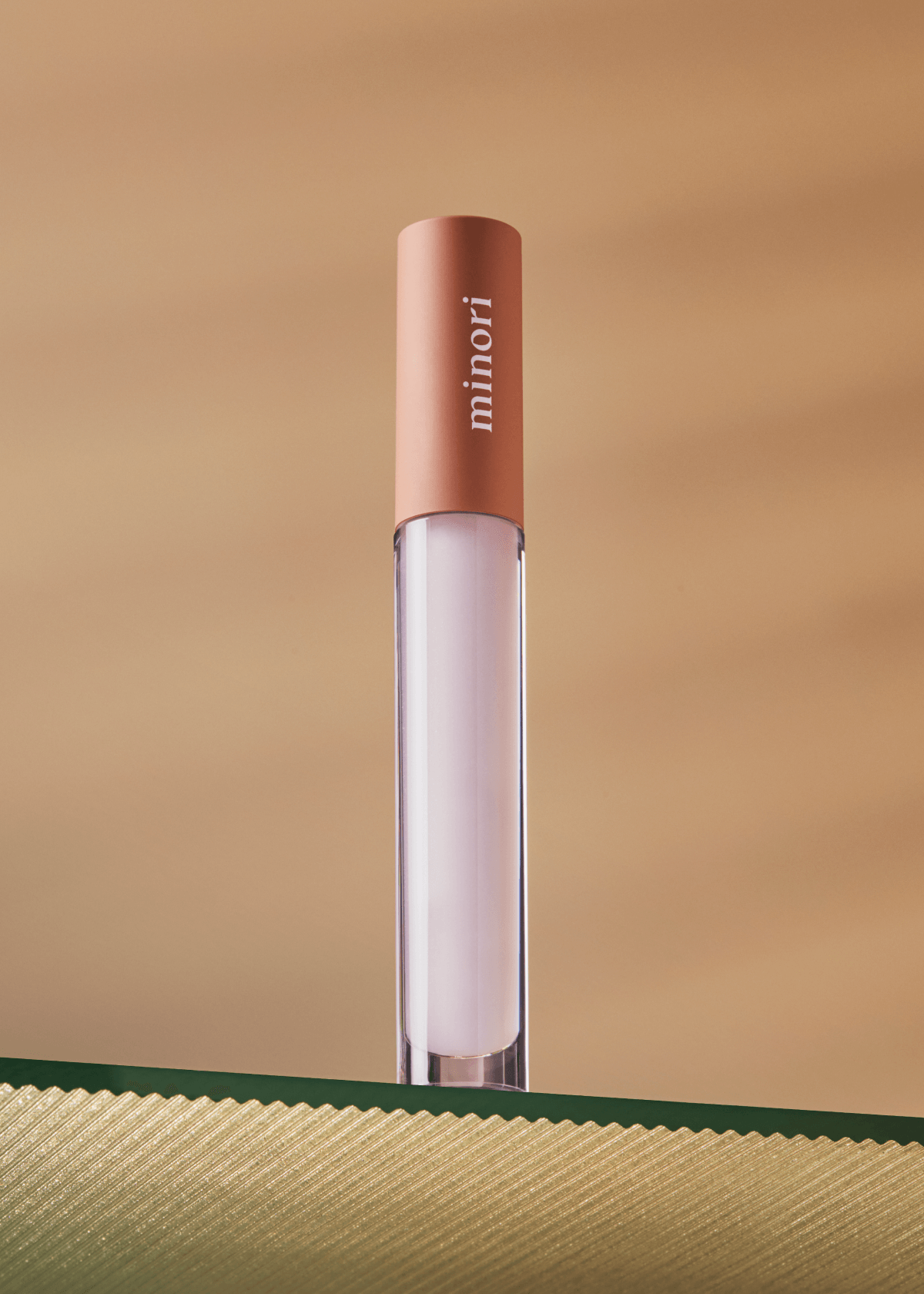 Lip gloss with 'minori' branding on a gold background