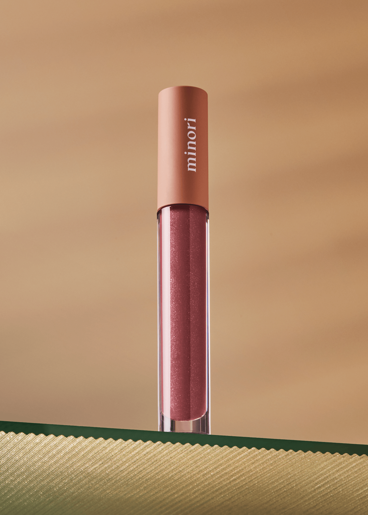 Lip gloss with 'minori' branding on a gold background