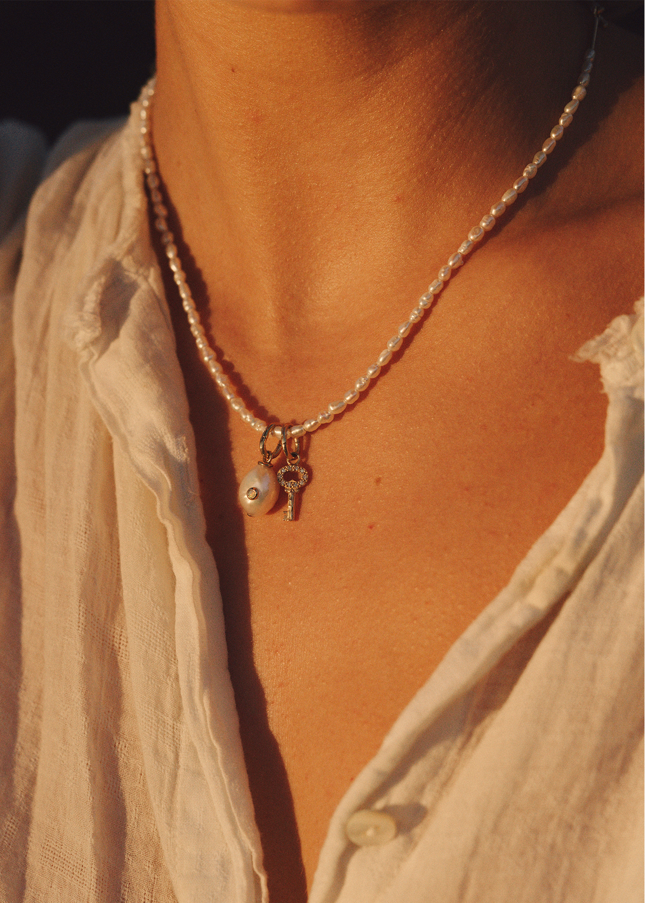 Pearl necklace with a pearl pendant worn on a women's neck. 