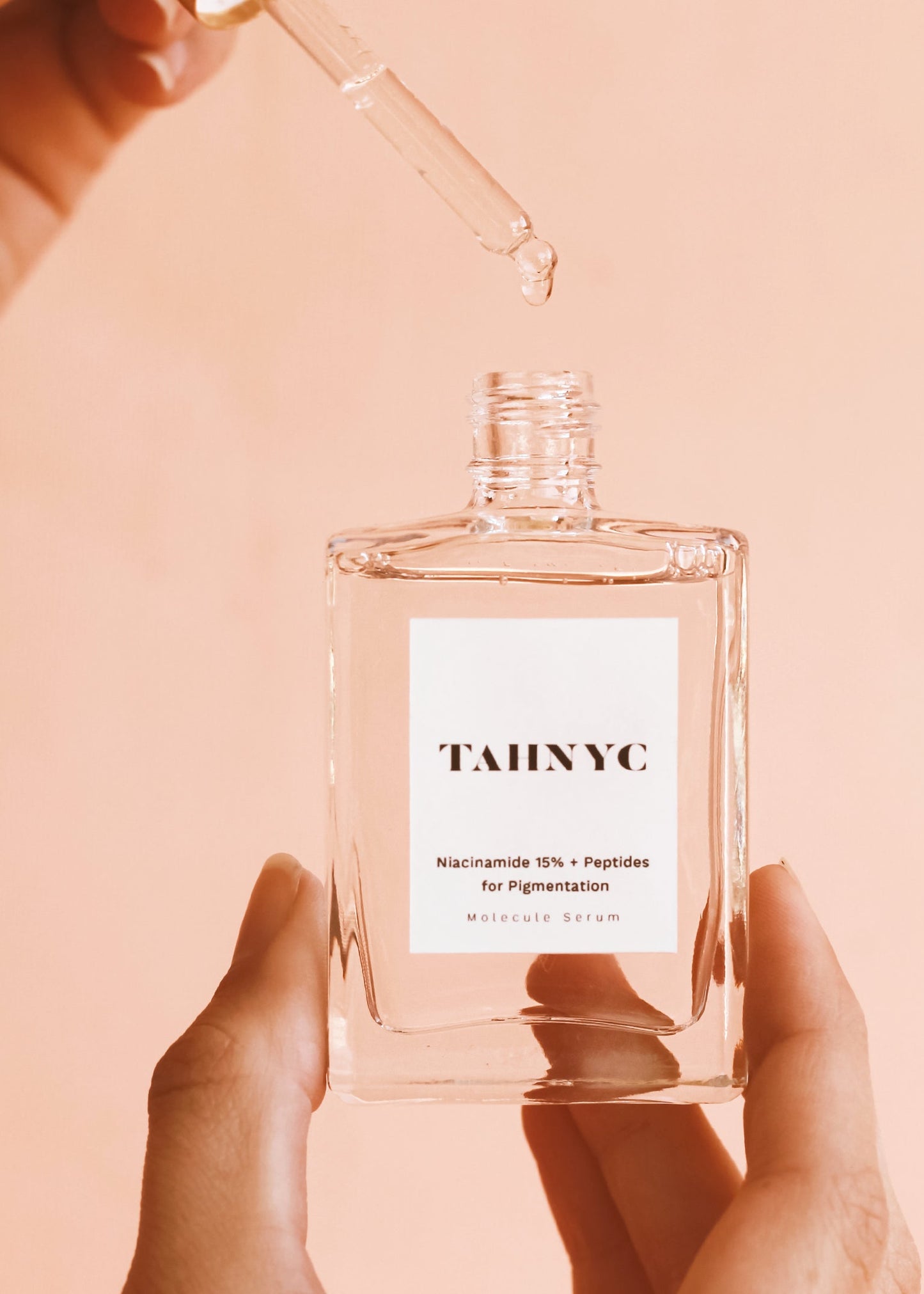 Clear bottle with a dropper labeled 'TAINYC' on a peach background