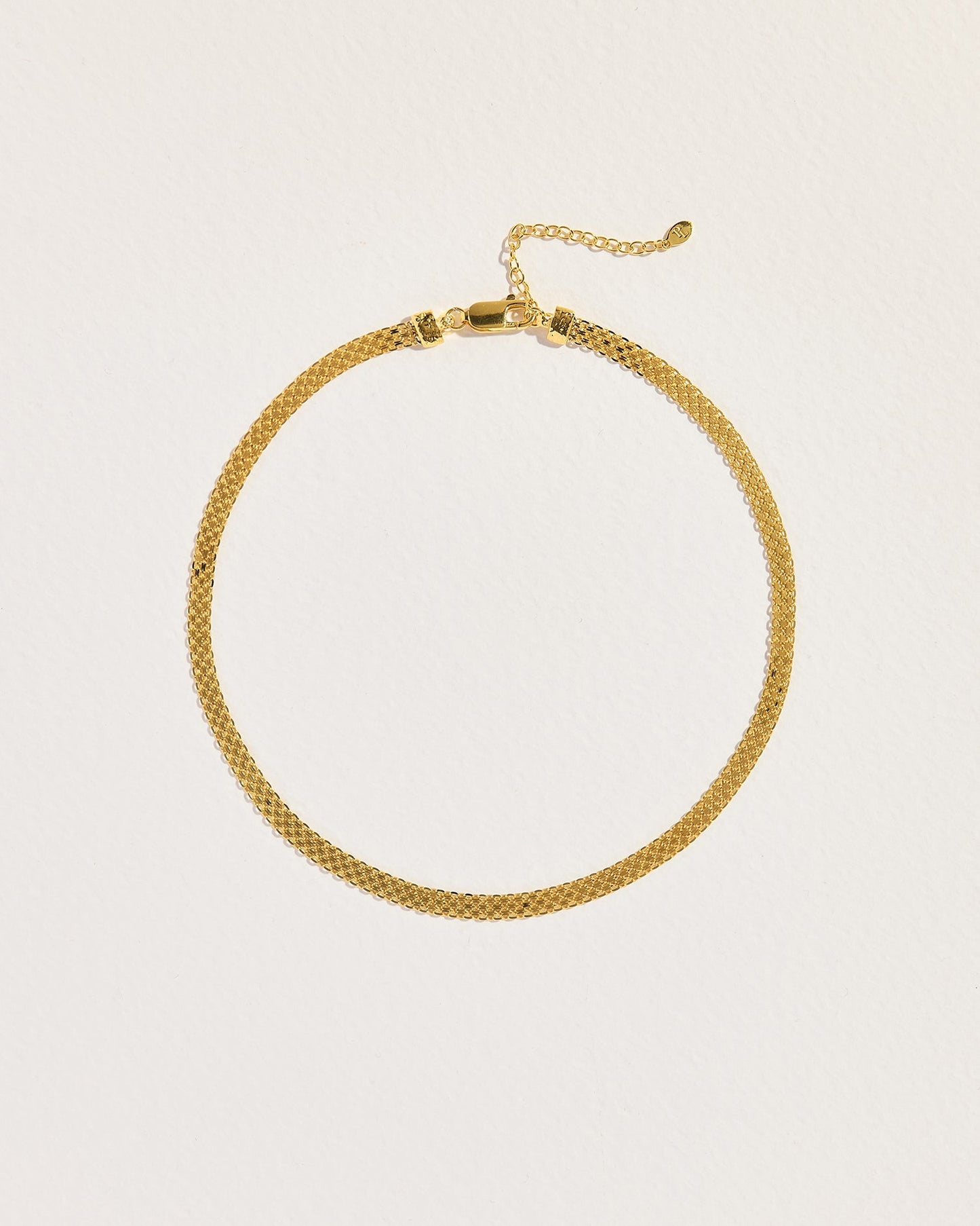Gold necklace on a light beige background