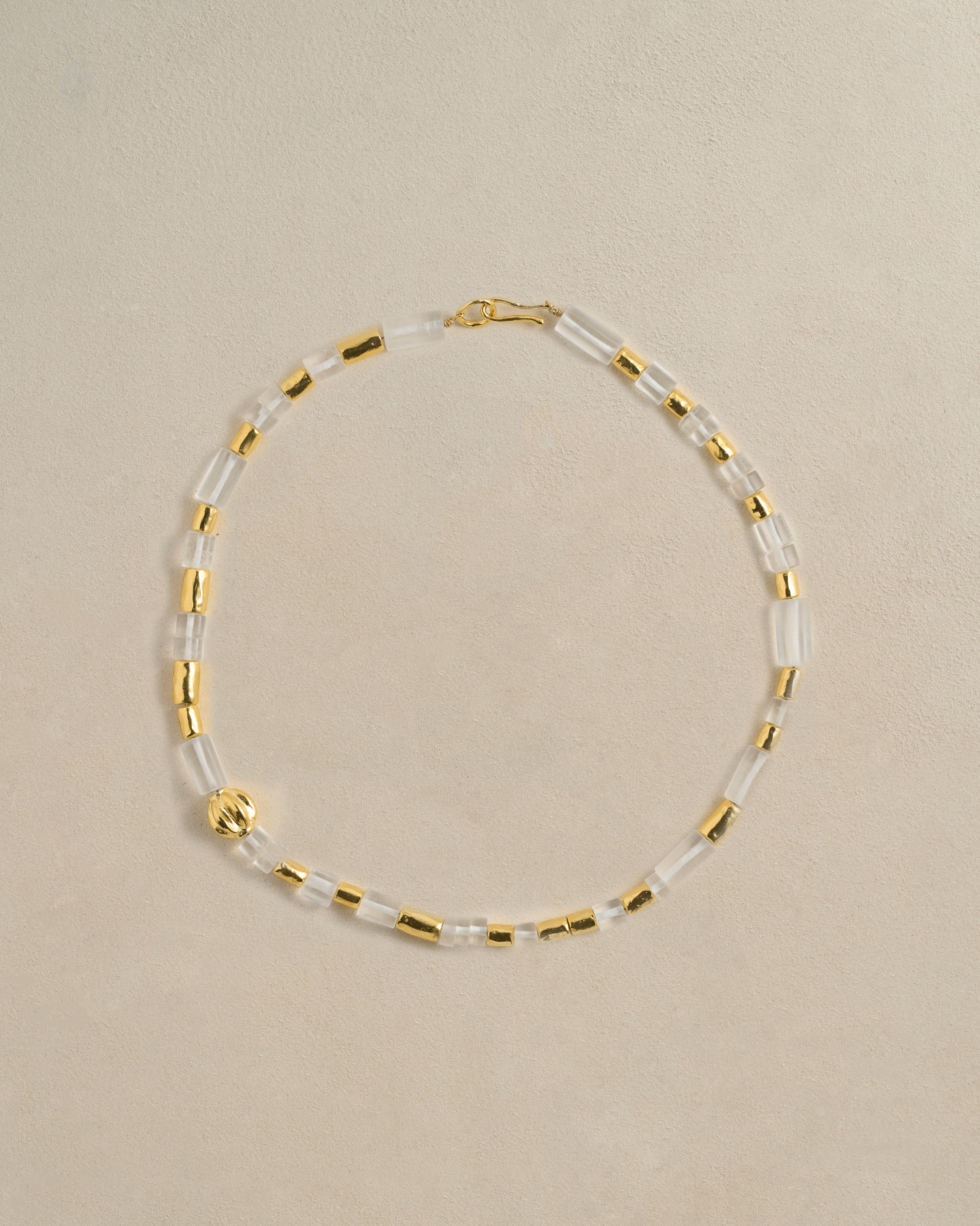 Necklace with gold and clear beads on a beige background