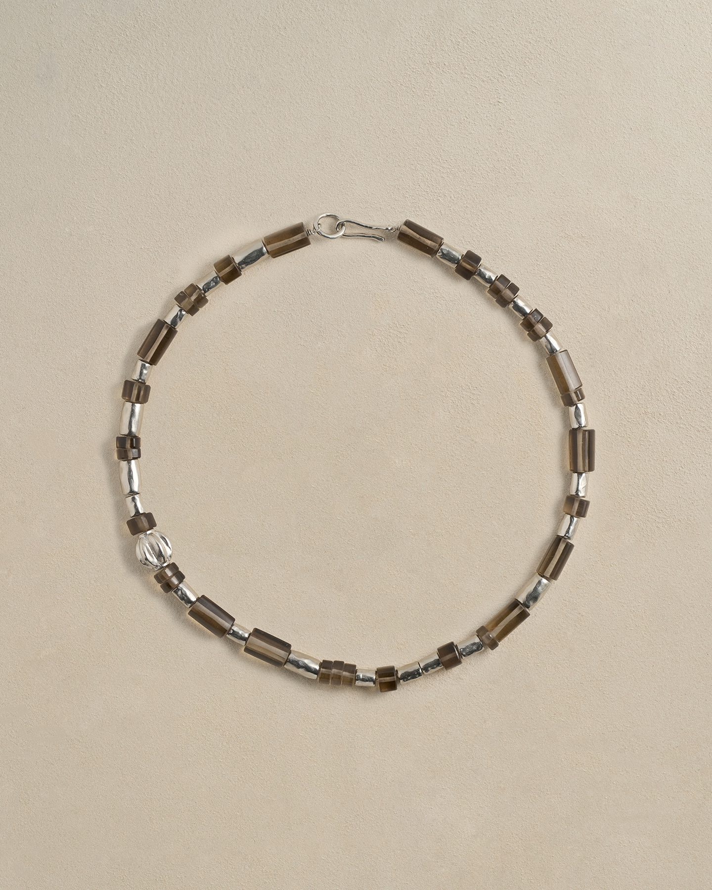 Necklace with brown and silver beads on a beige background
