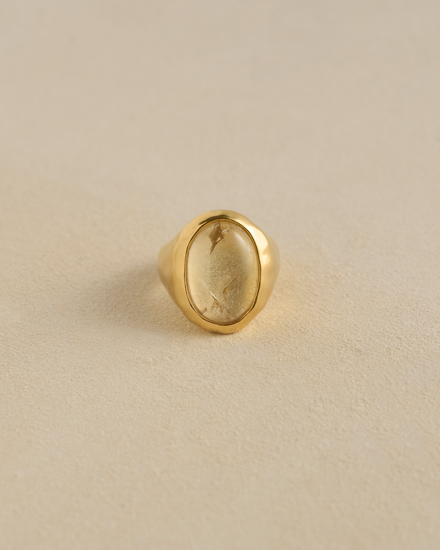 Gold ring with a stone on a beige background