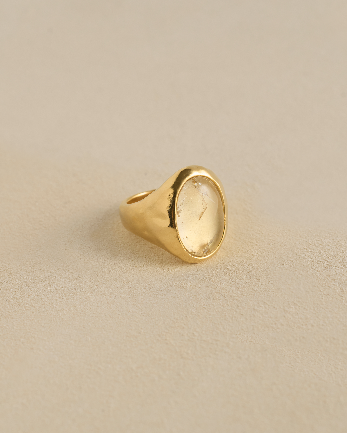 Gold ring with a clear stone on a beige background