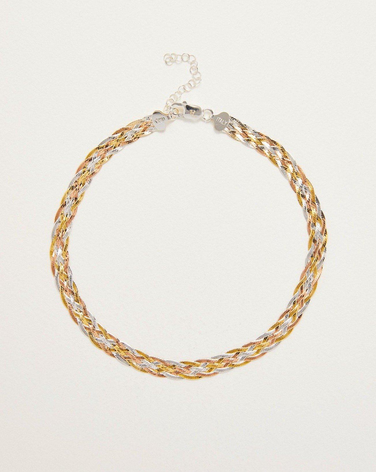 Gold and silver braided necklace on a light beige background