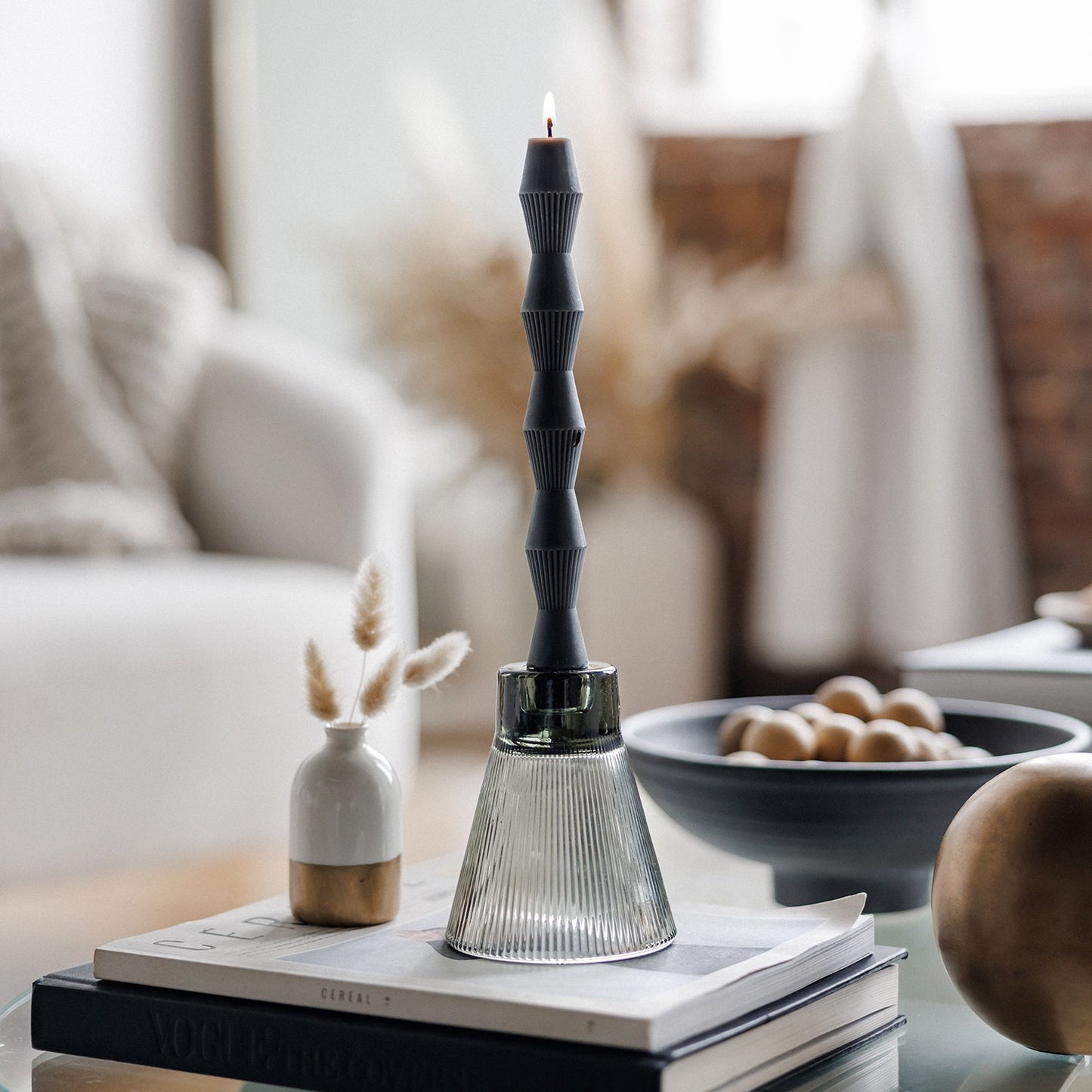 Black pillar candle in glass base on a coffee table