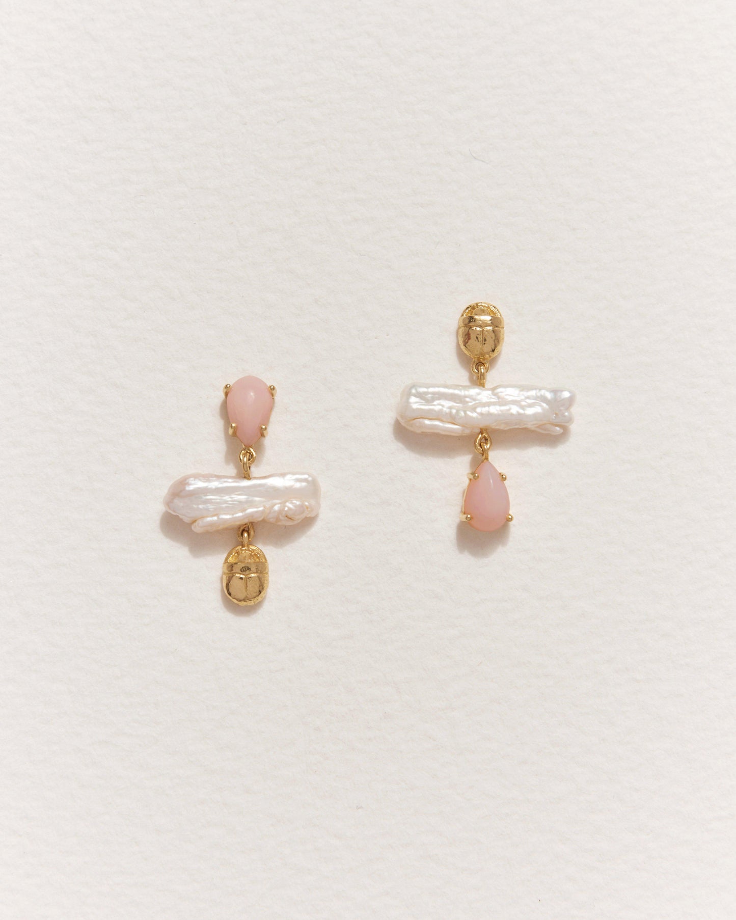 Pair of earrings with pink stones and gold accents on a light gray background