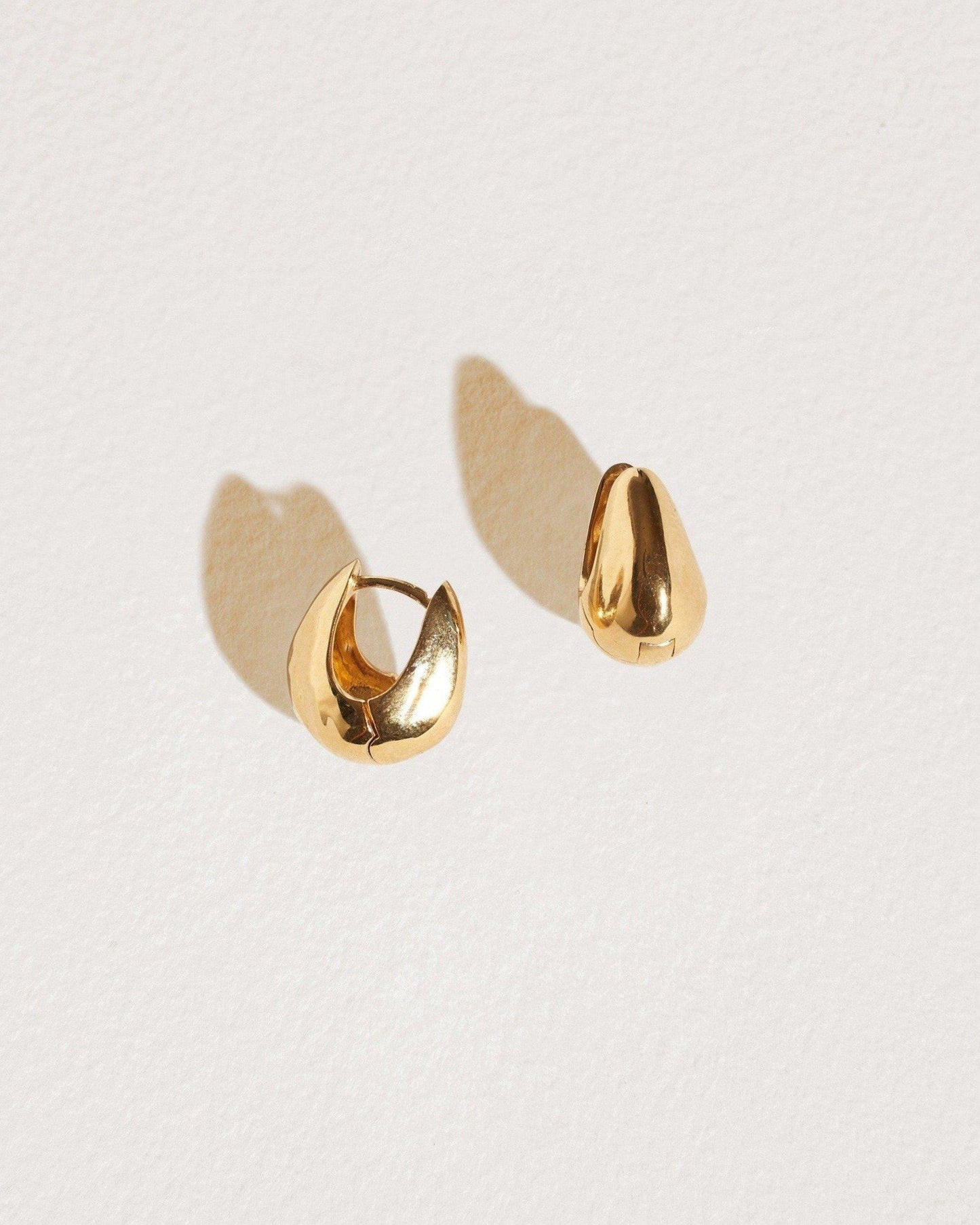 Gold hoop earrings on a light beige background