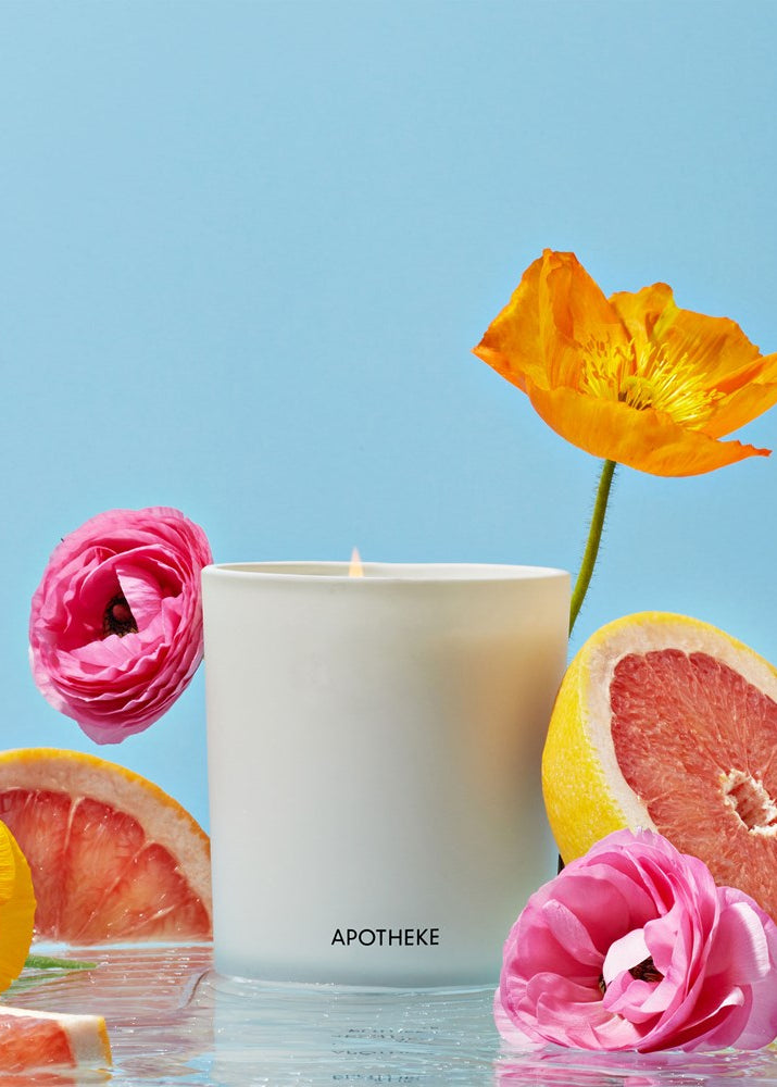 White candle with flowers and grapefruit on a blue background