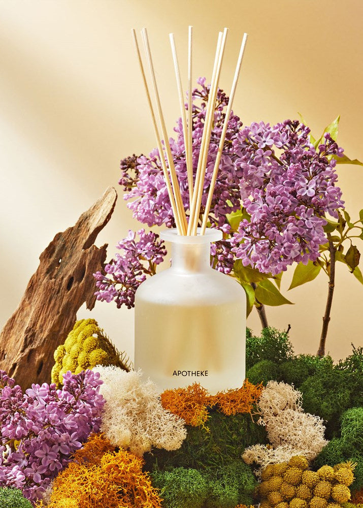 Aromatherapy diffuser with purple flowers and greenery on a neutral background