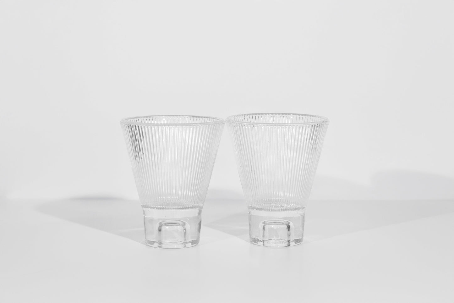 Two clear ribbed glasses on a white background