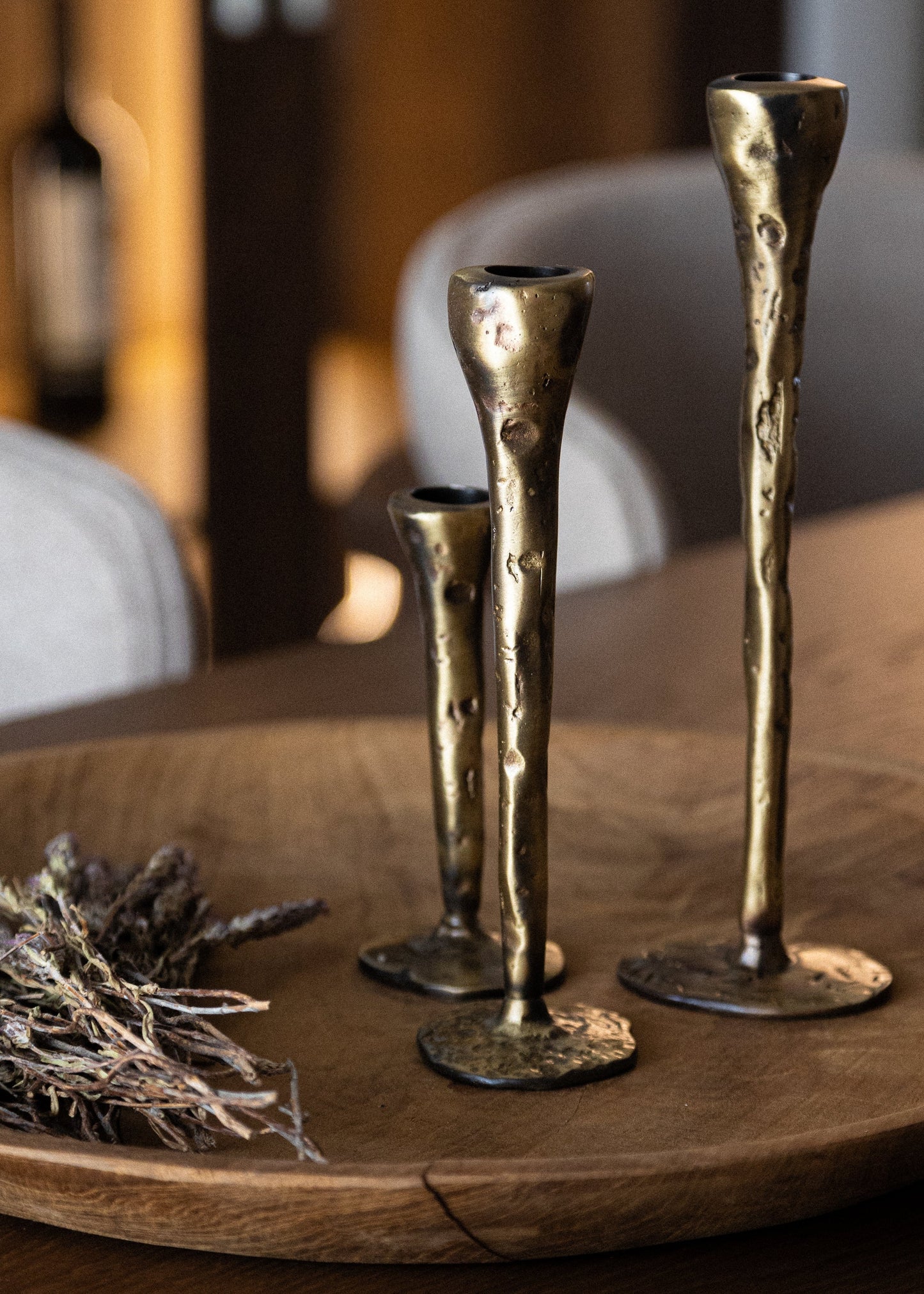 Three gold candle holders on a wooden tray with dried lavender, blurred background