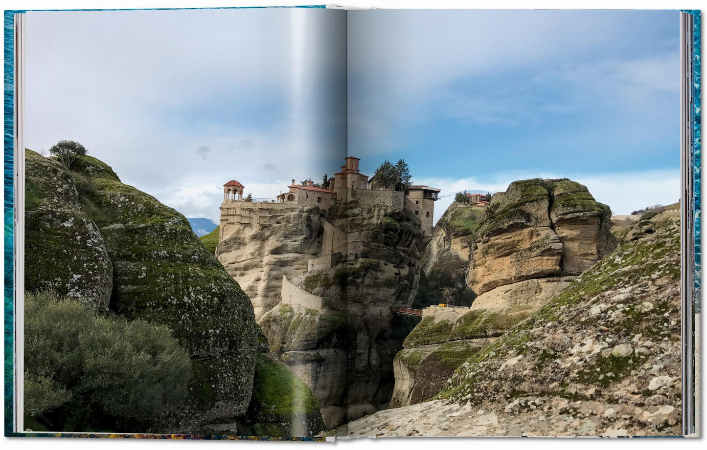 Monastery built into a cliffside with rocky landscape and blue sky.