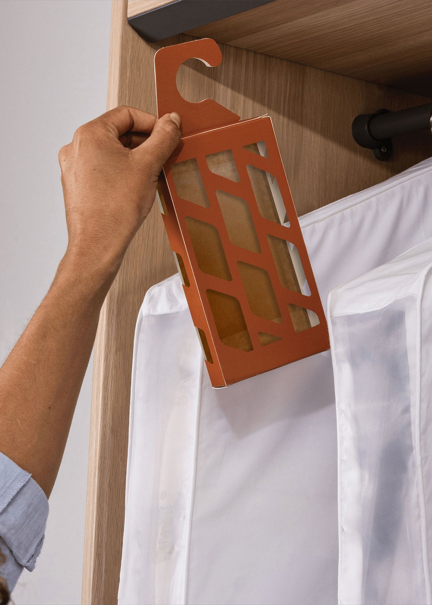 Person hanging a moth trap in a closet.