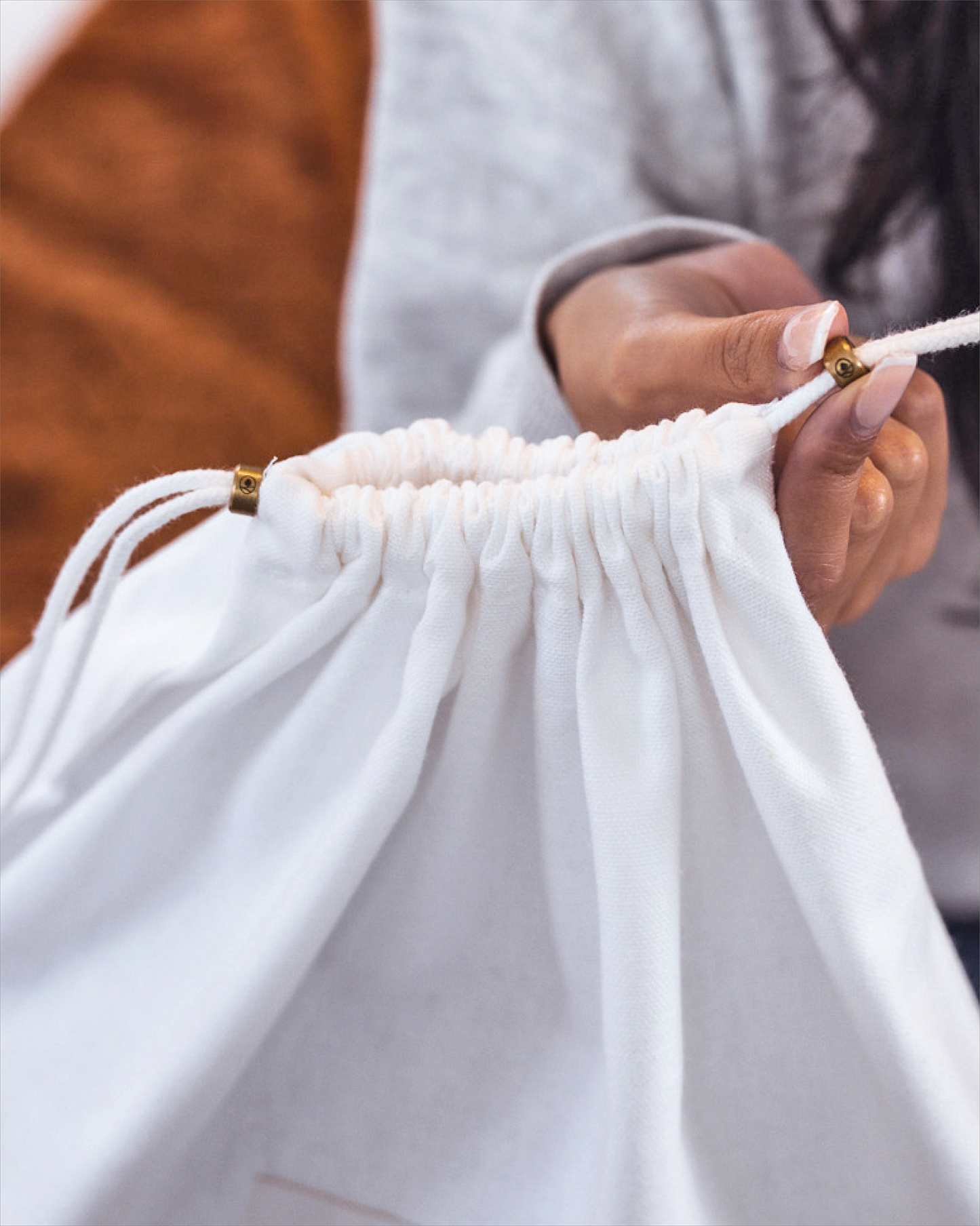 Person holding a white drawstring bag with a blurred background