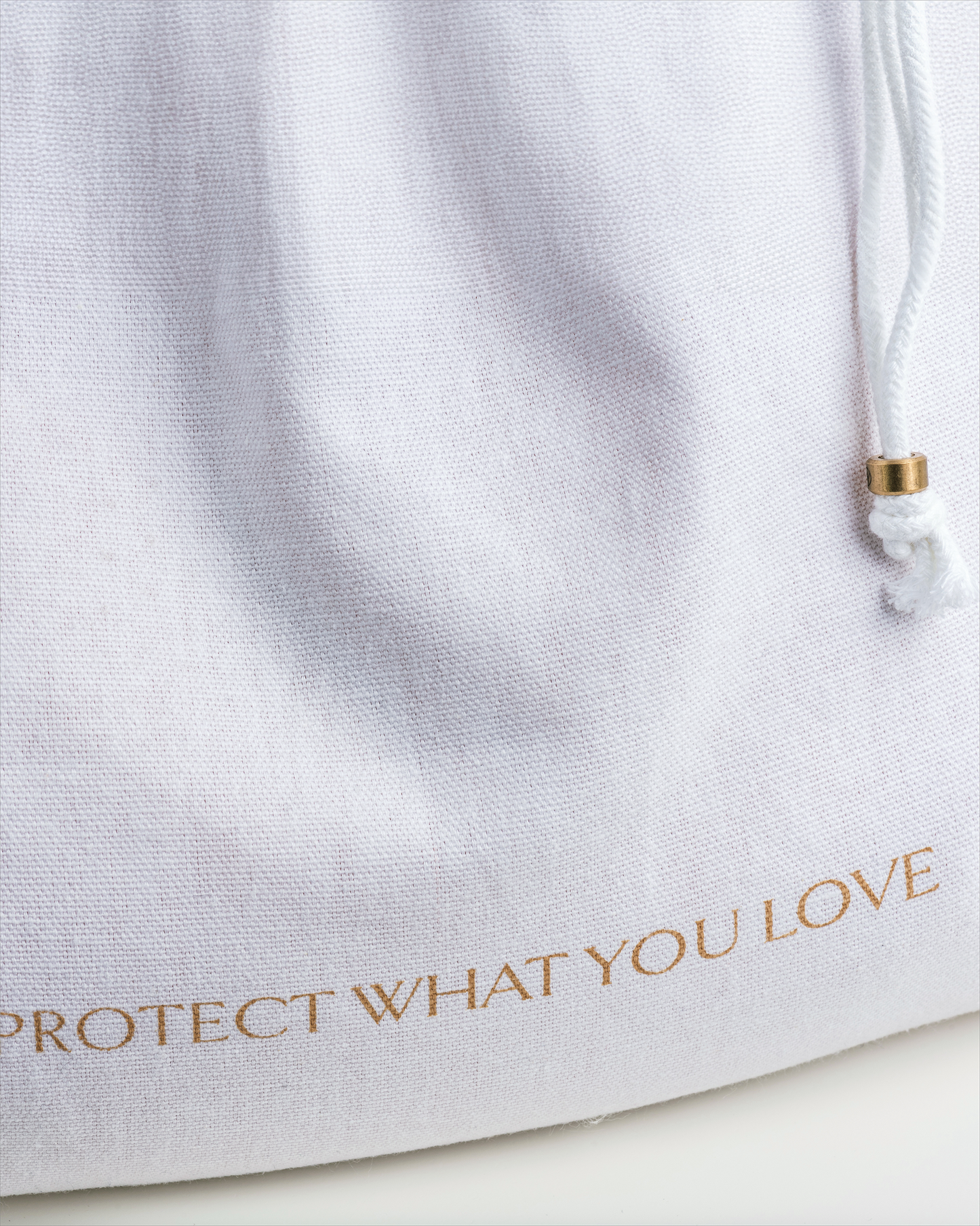 White drawstring bag with 'Protect What You Love' text in gold on a white background