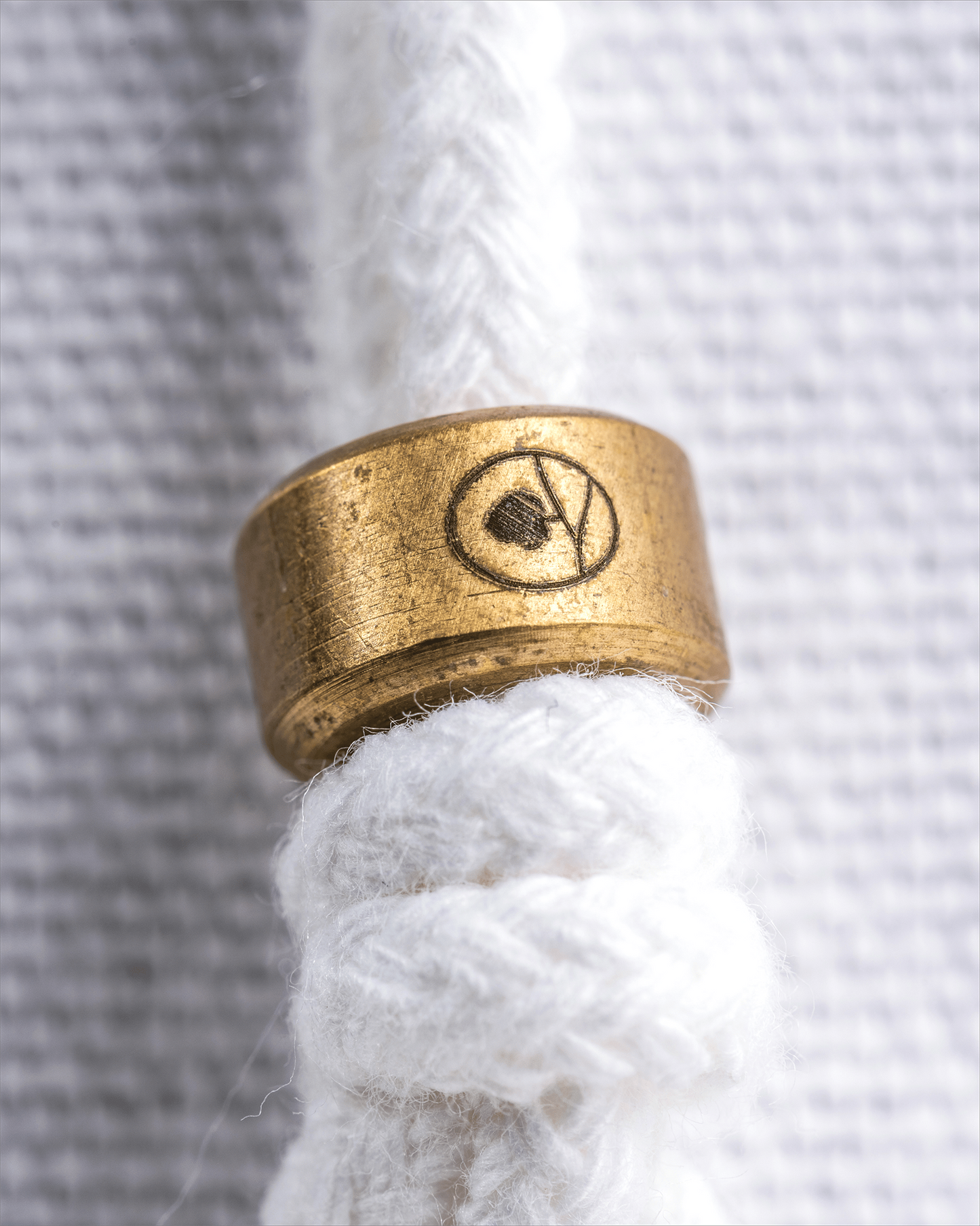 Gold cord stopper with a logo on a white rope against a textured gray background