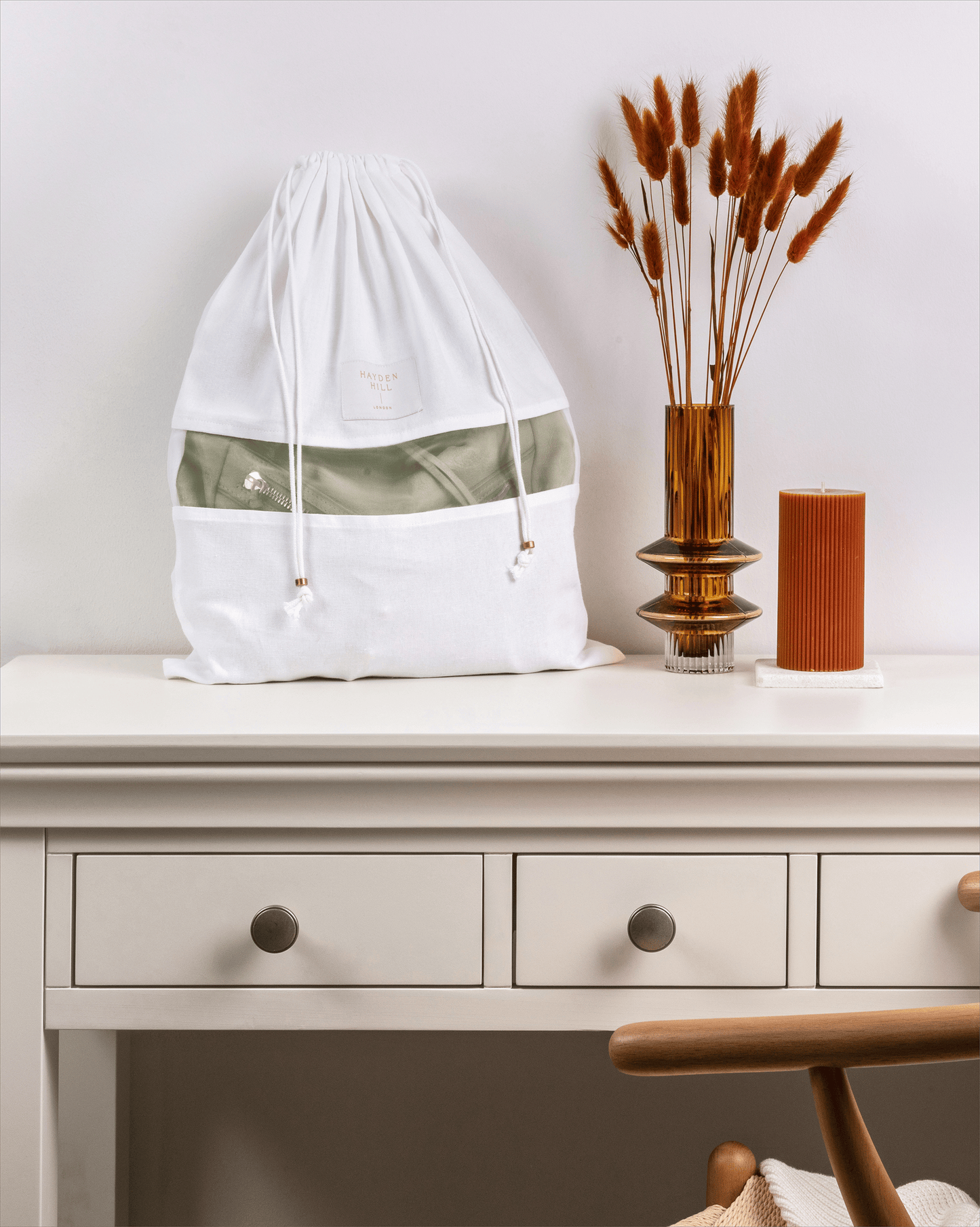 White drawstring bag with green accent on a white surface with decorative items.