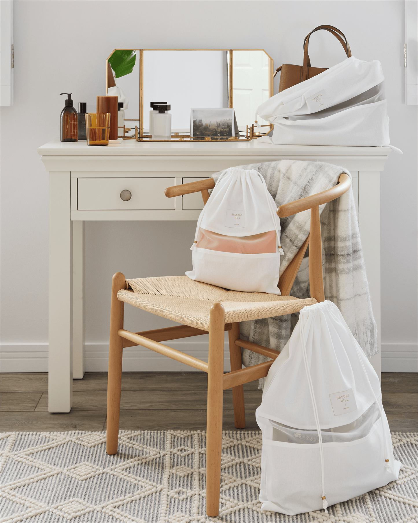 Wooden chair with a white drawstring bag on a rug in a room with a vanity table.