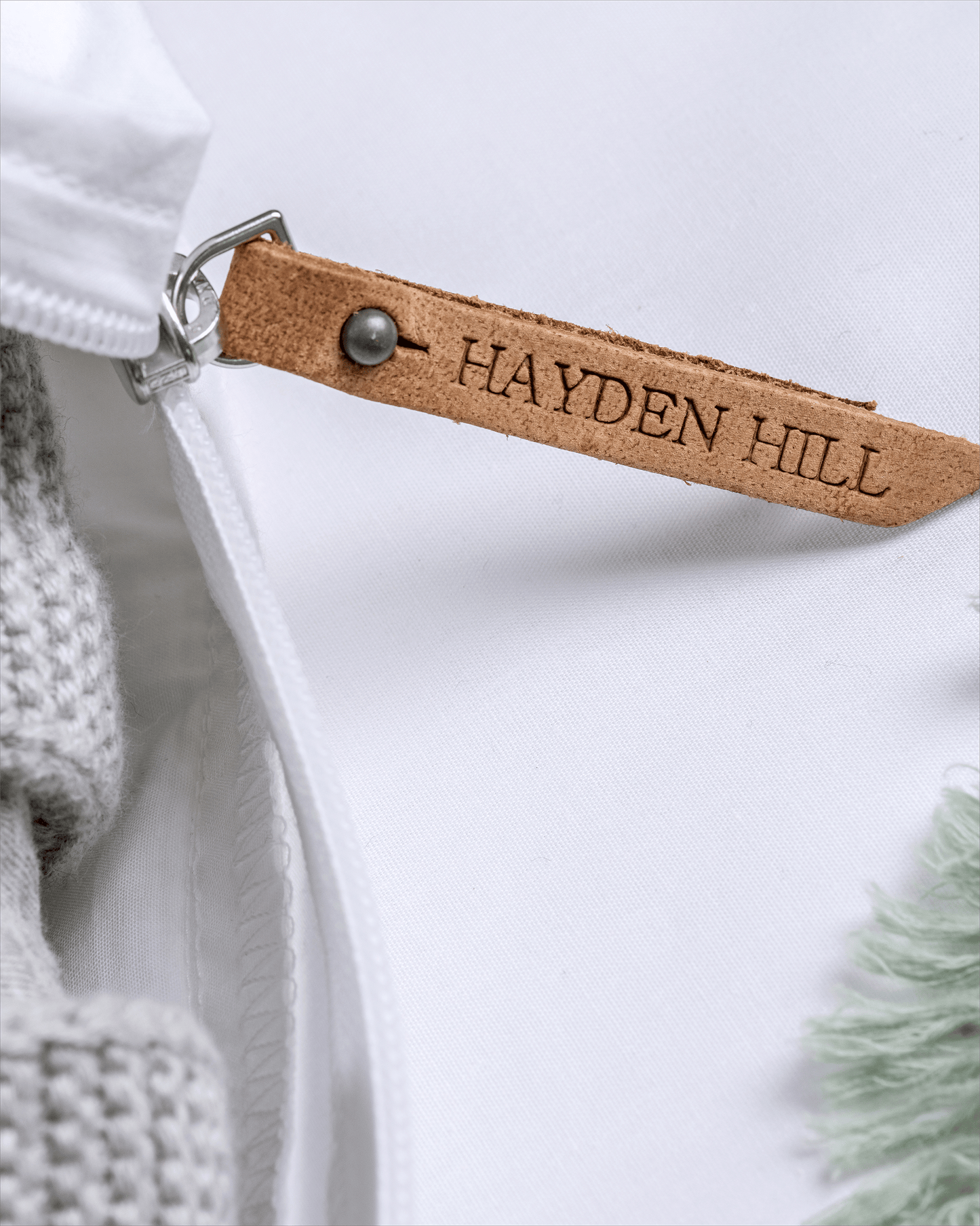 Close-up of a white garment with a brown leather tag labeled 'Hayden Hill'.