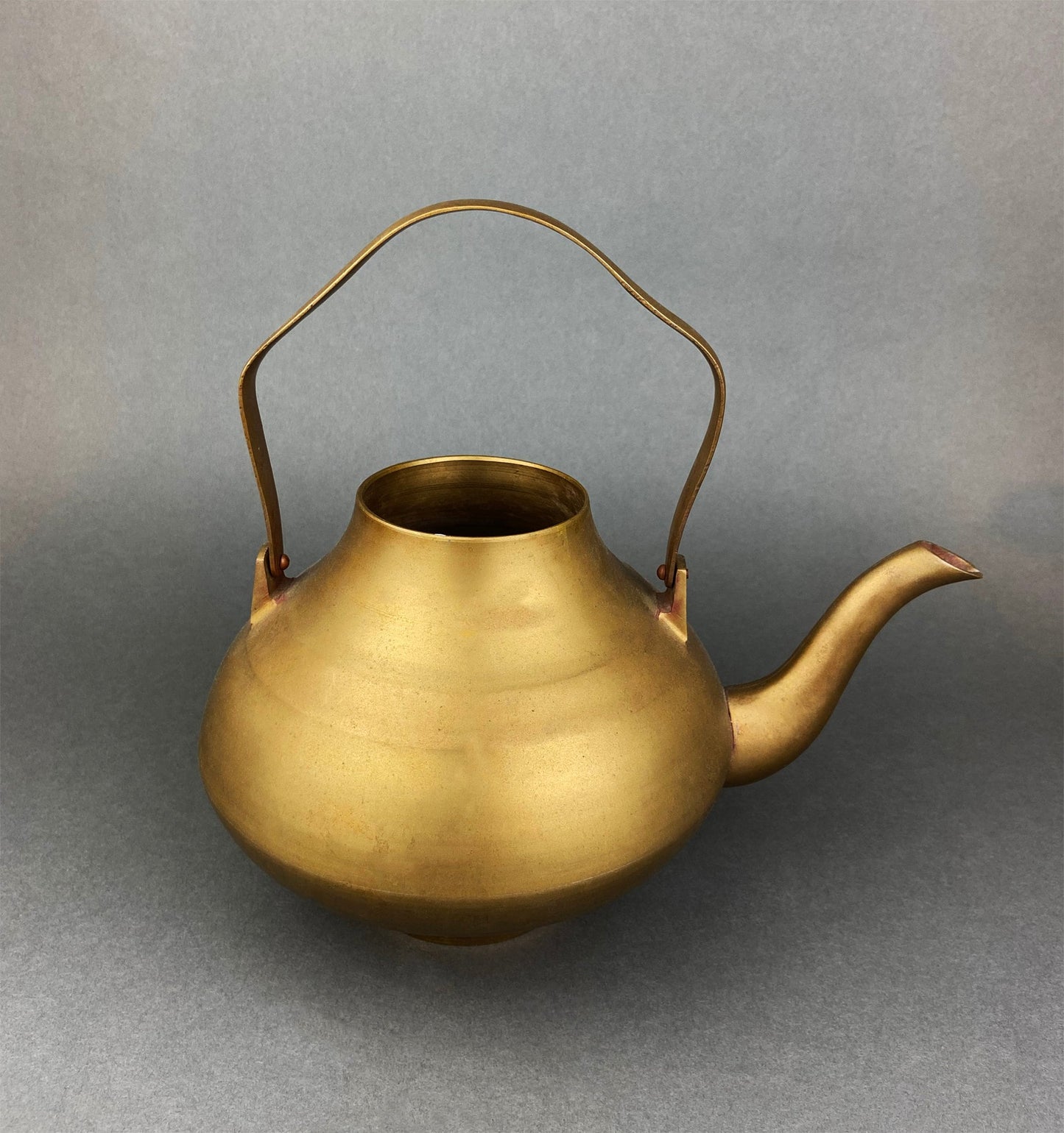 Brass teapot on a gray background