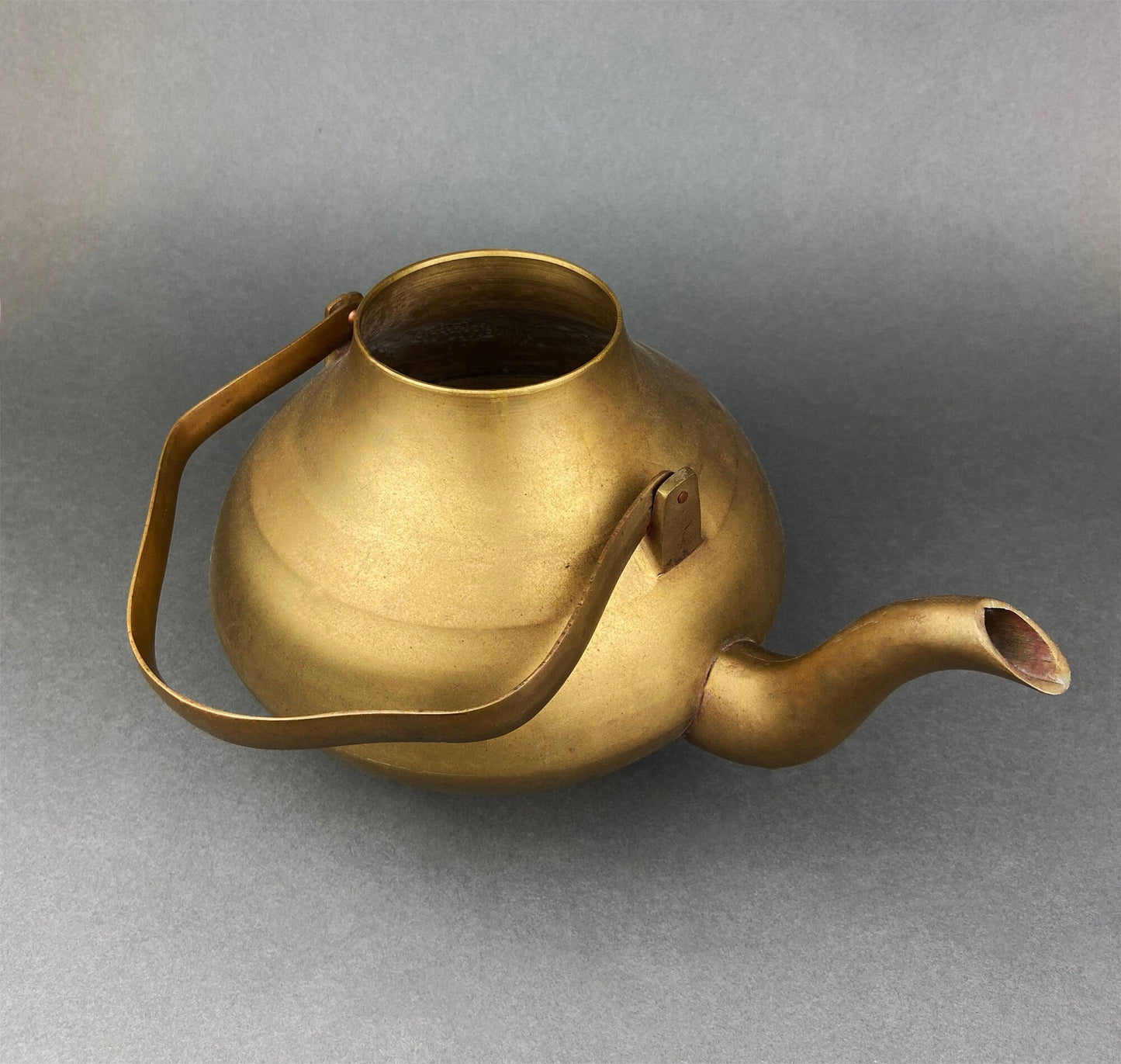 Brass teapot on a gray background