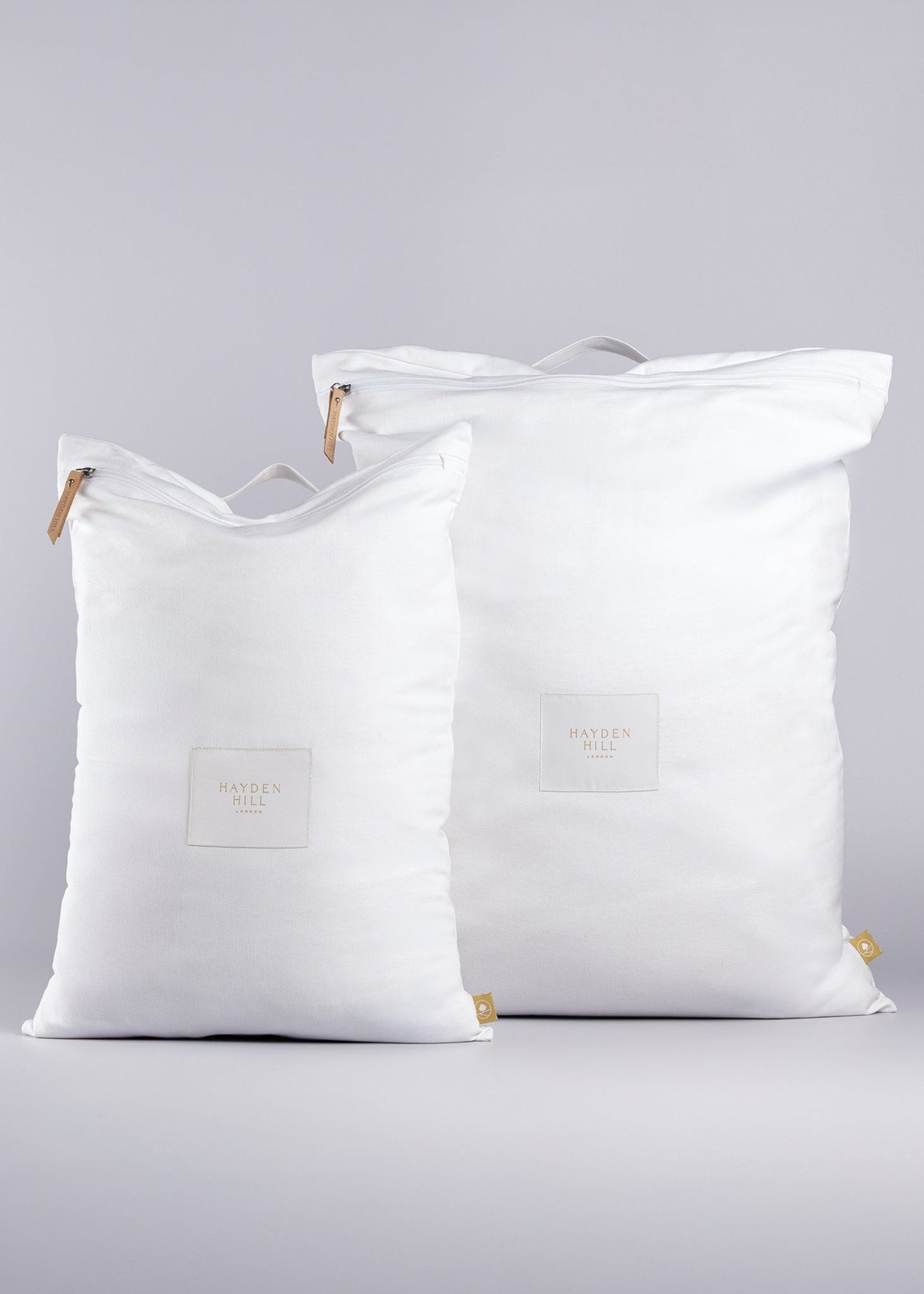 Two white organic cotton travel laundry bags with zippers ona a light background