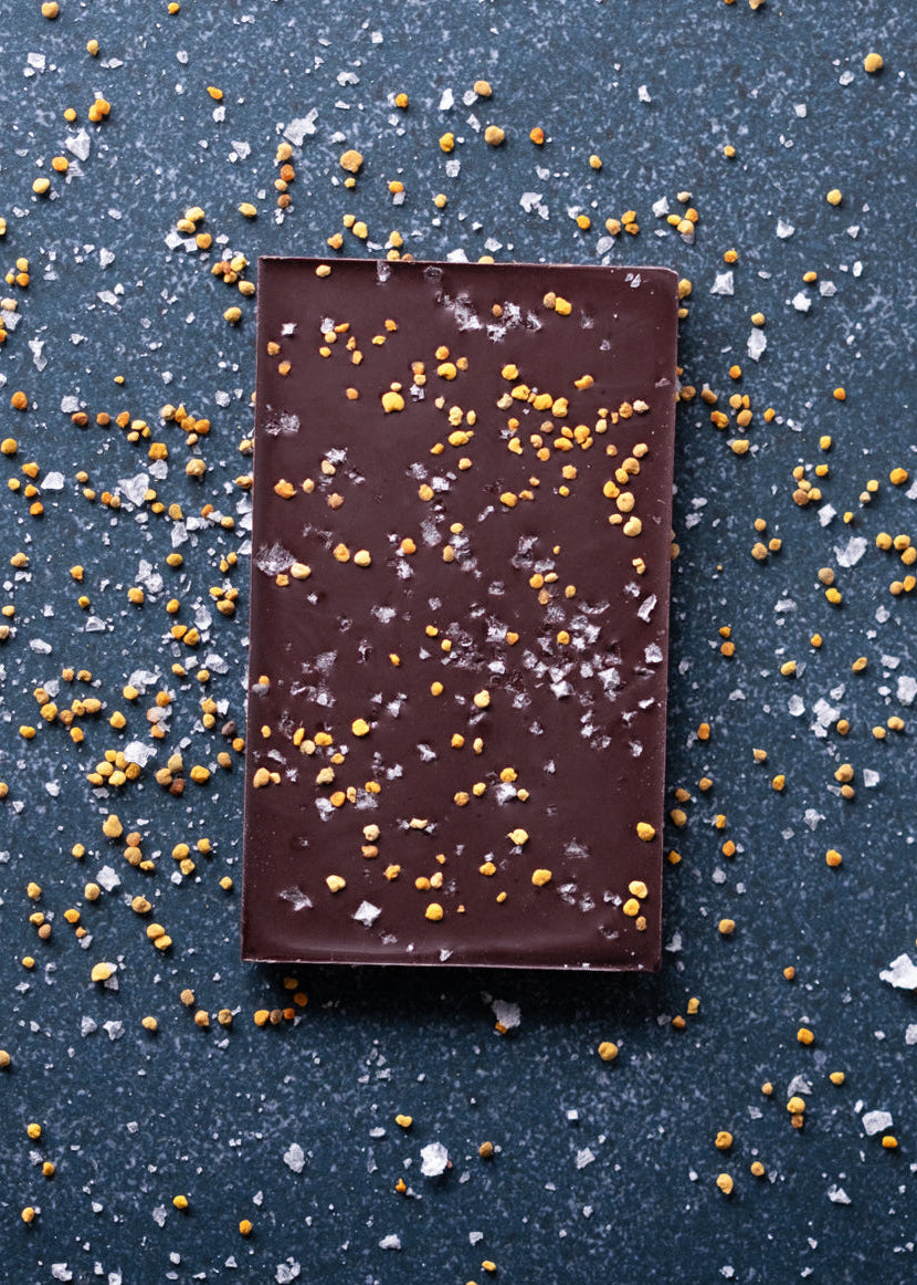 Dark chocolate bar with pollen pecks on a dark surface