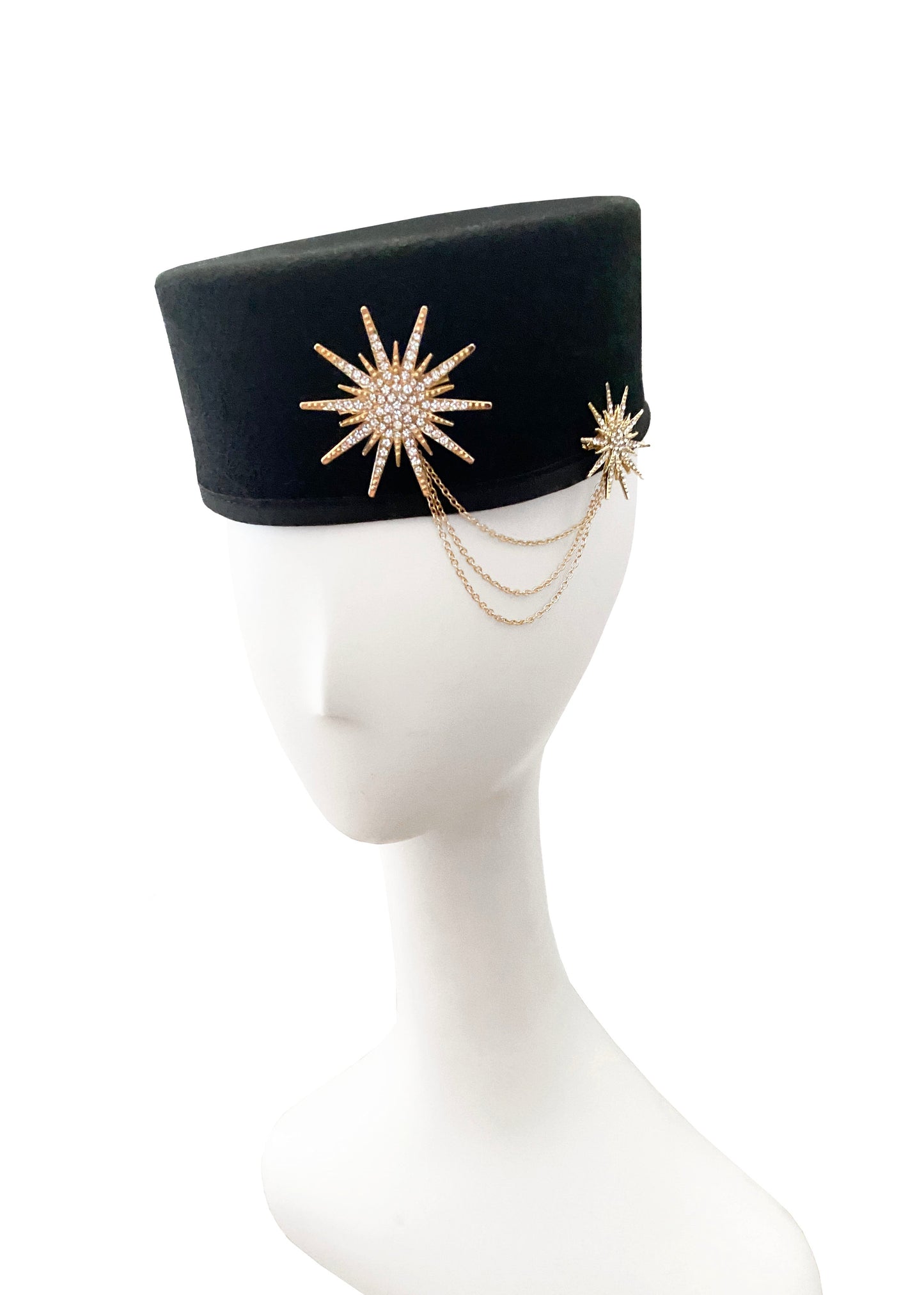 Black felt hat with gold starburst accessory on a mannequin head against a white background