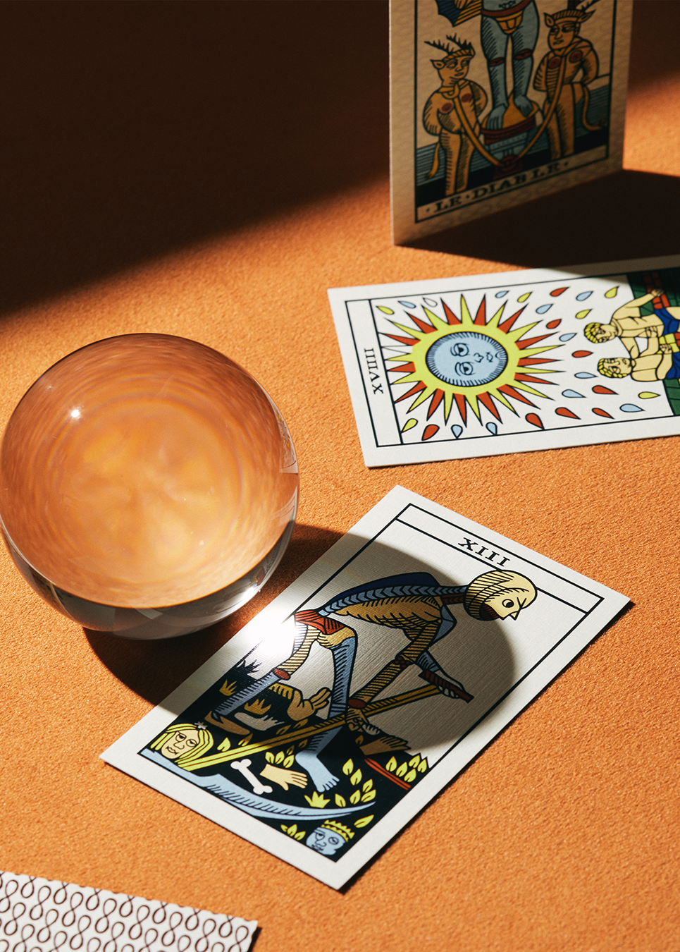 Tarot cards and a crystal ball on an orange surface