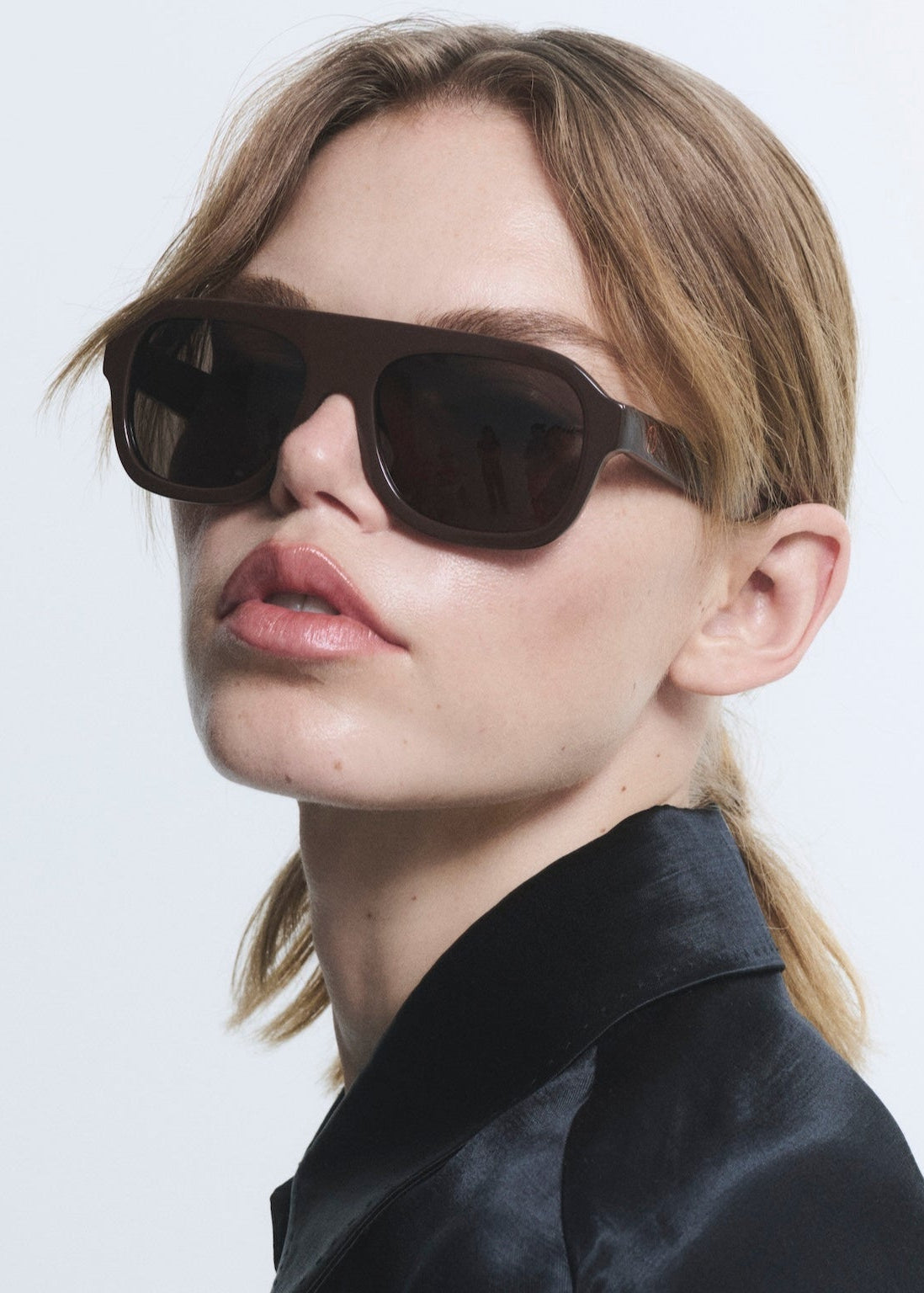 Woman wearing dark sunglasses against a light background